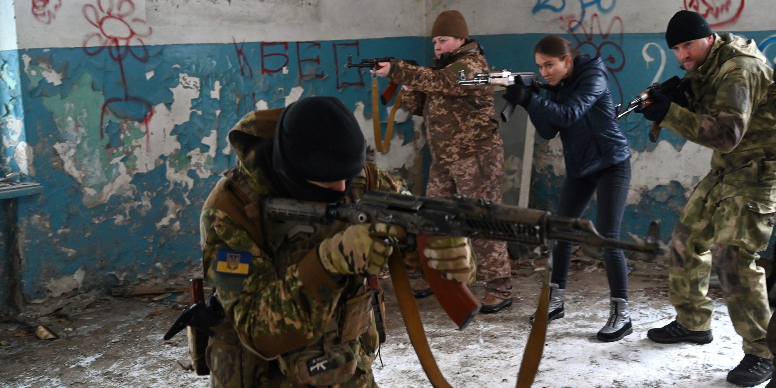 A military instructor teaches civilians holding wooden replicas of Kalashnikov rifles, during a training session at an abandoned factory in the Ukrainian capital of Kyiv on January 30, 2022.