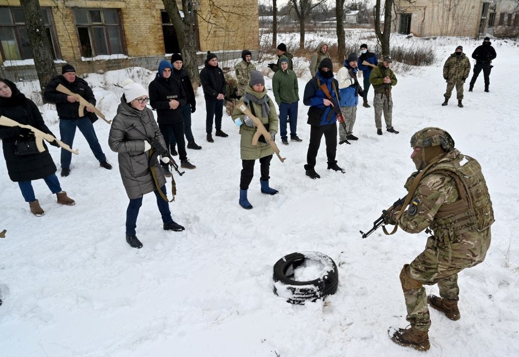 A military instructor teaches civilians holding wooden replicas of Kalashnikov rifles, during a training session at an abandoned factory in the Ukrainian capital of Kyiv on January 30, 2022.