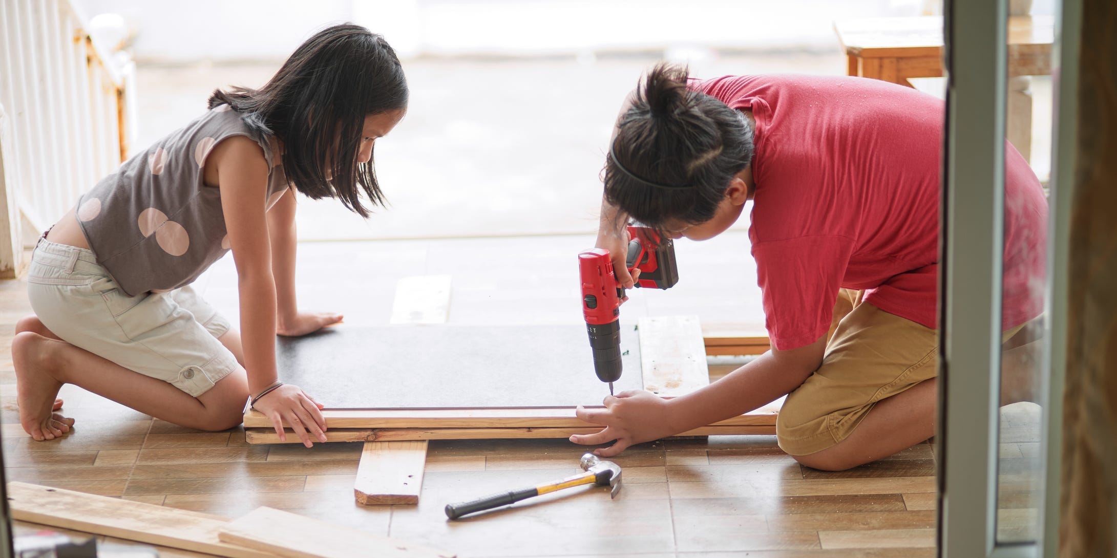 Two children using a drill to make a chalkboard