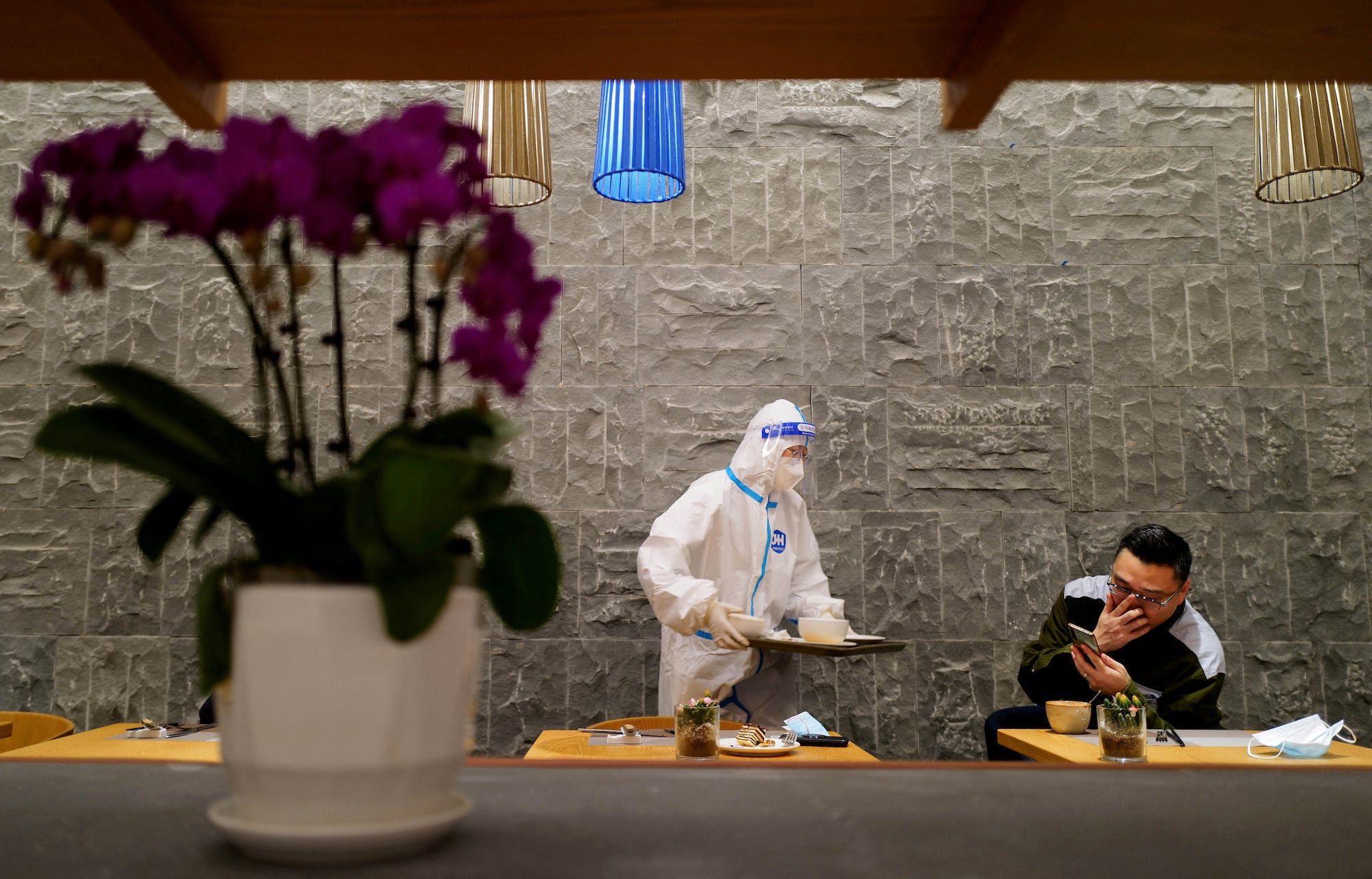 A waiter in full PPE serves a man
