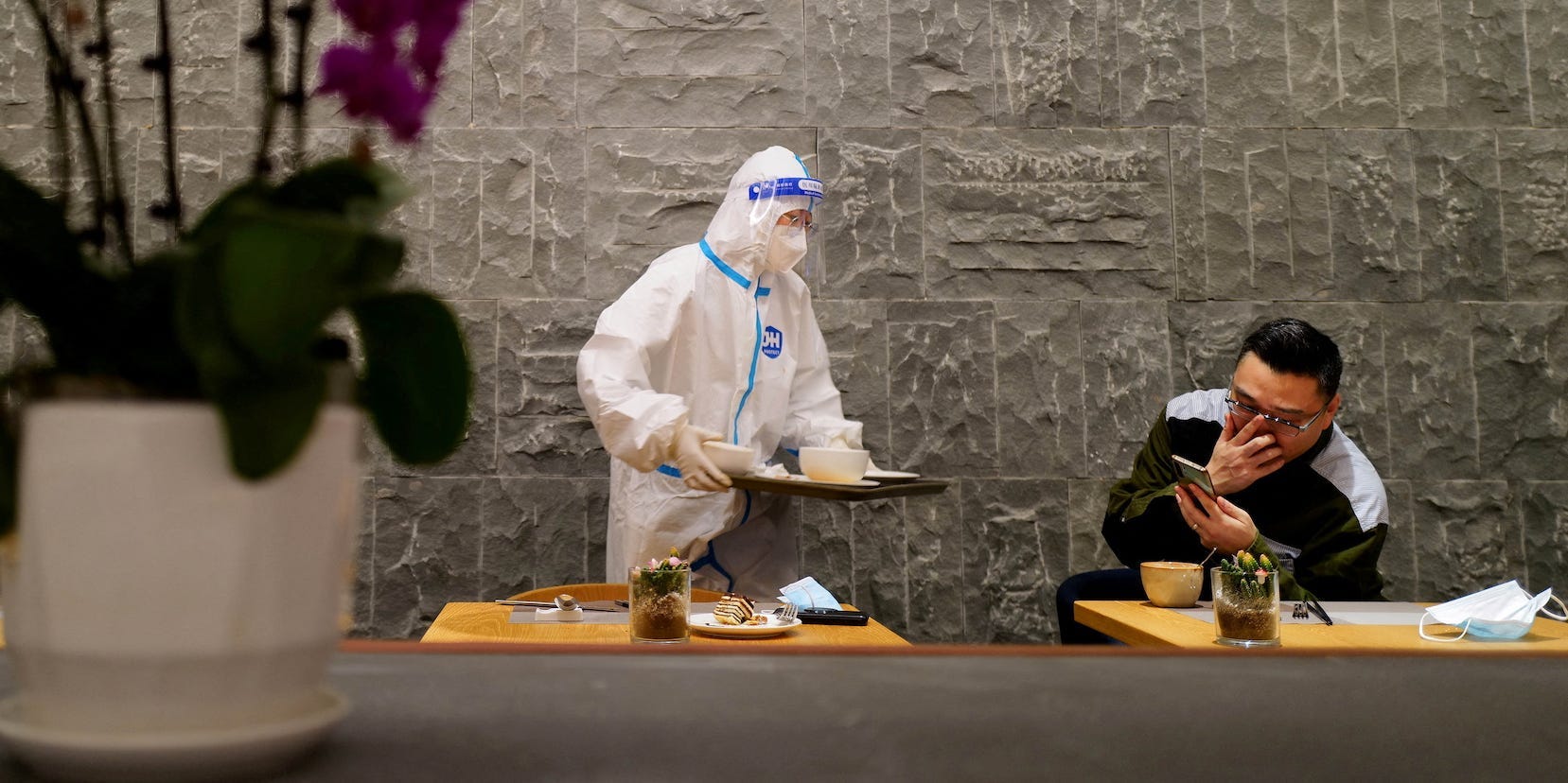 A waiter in full PPE serves a man