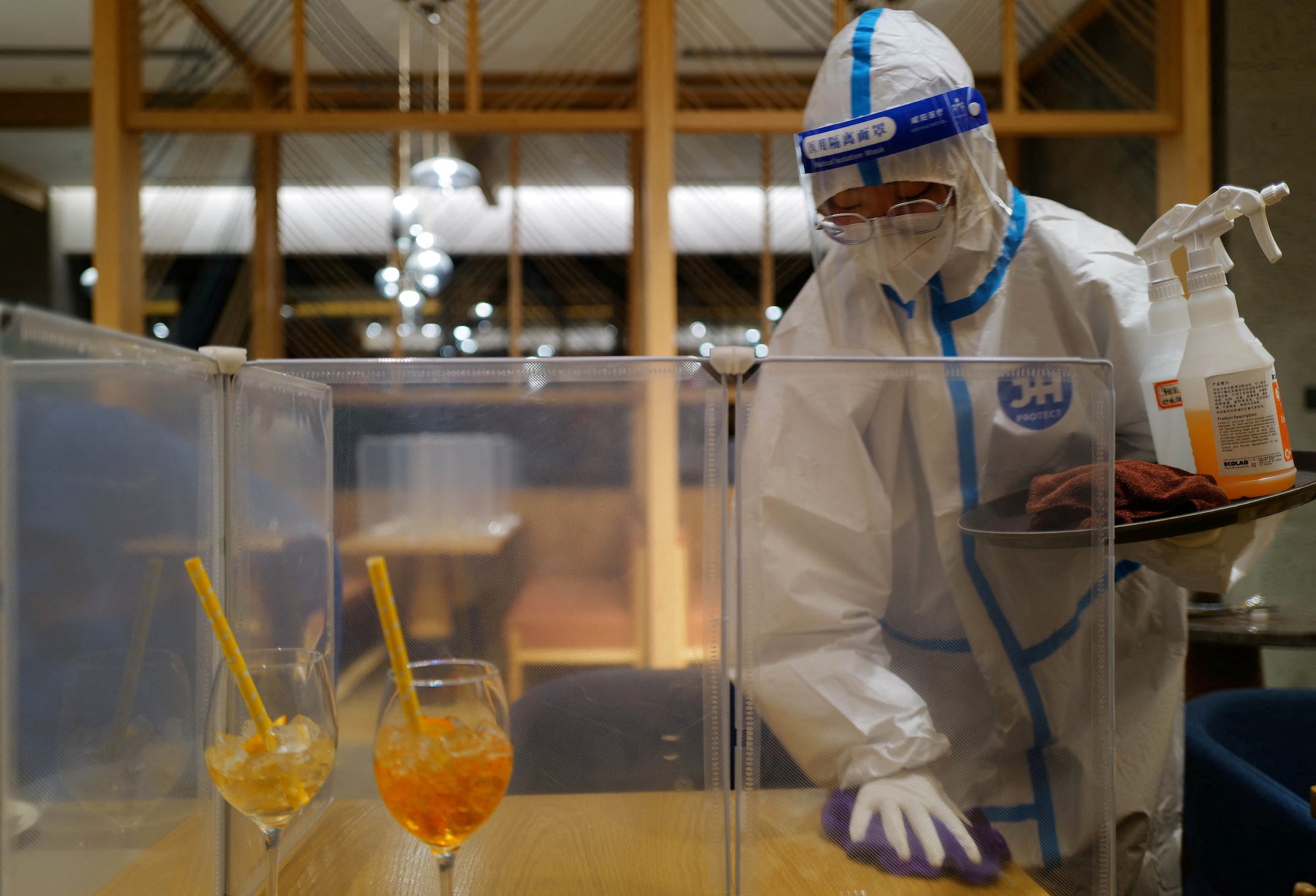 A waiter wears full PPE while cleaning a table.