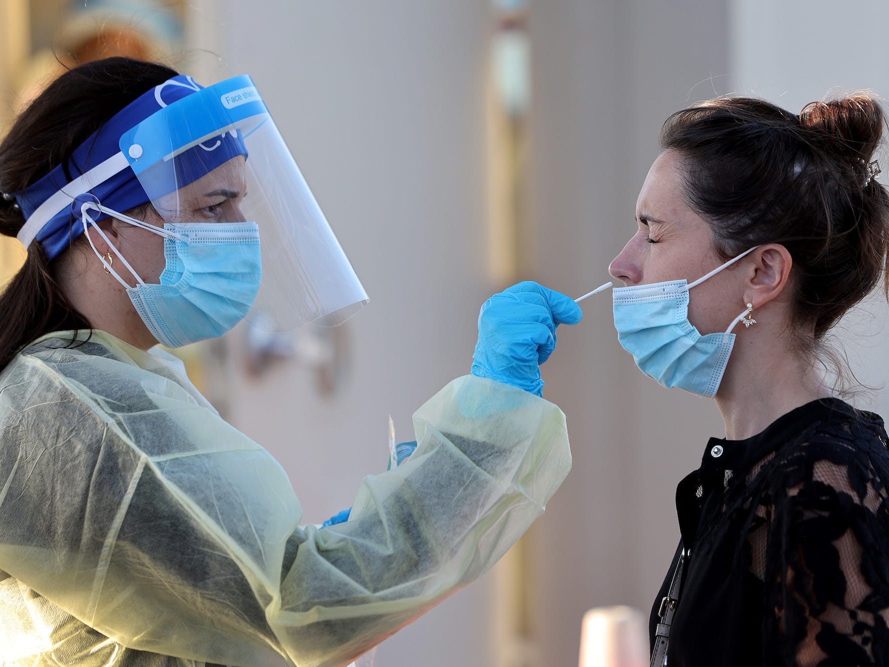 A healthcare worker in full PPE does a COVID-19 test on a woman wearing a mark in Florida in January 2022.