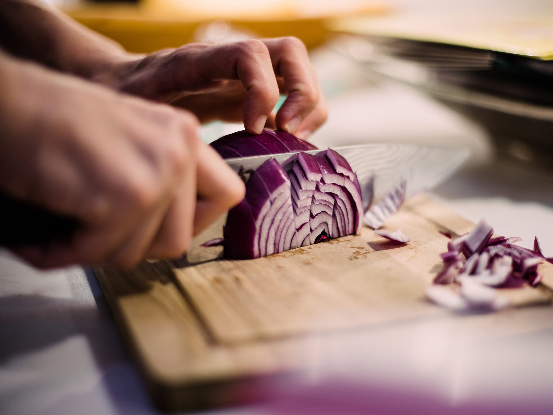 Person dicing red onion on a cutting board