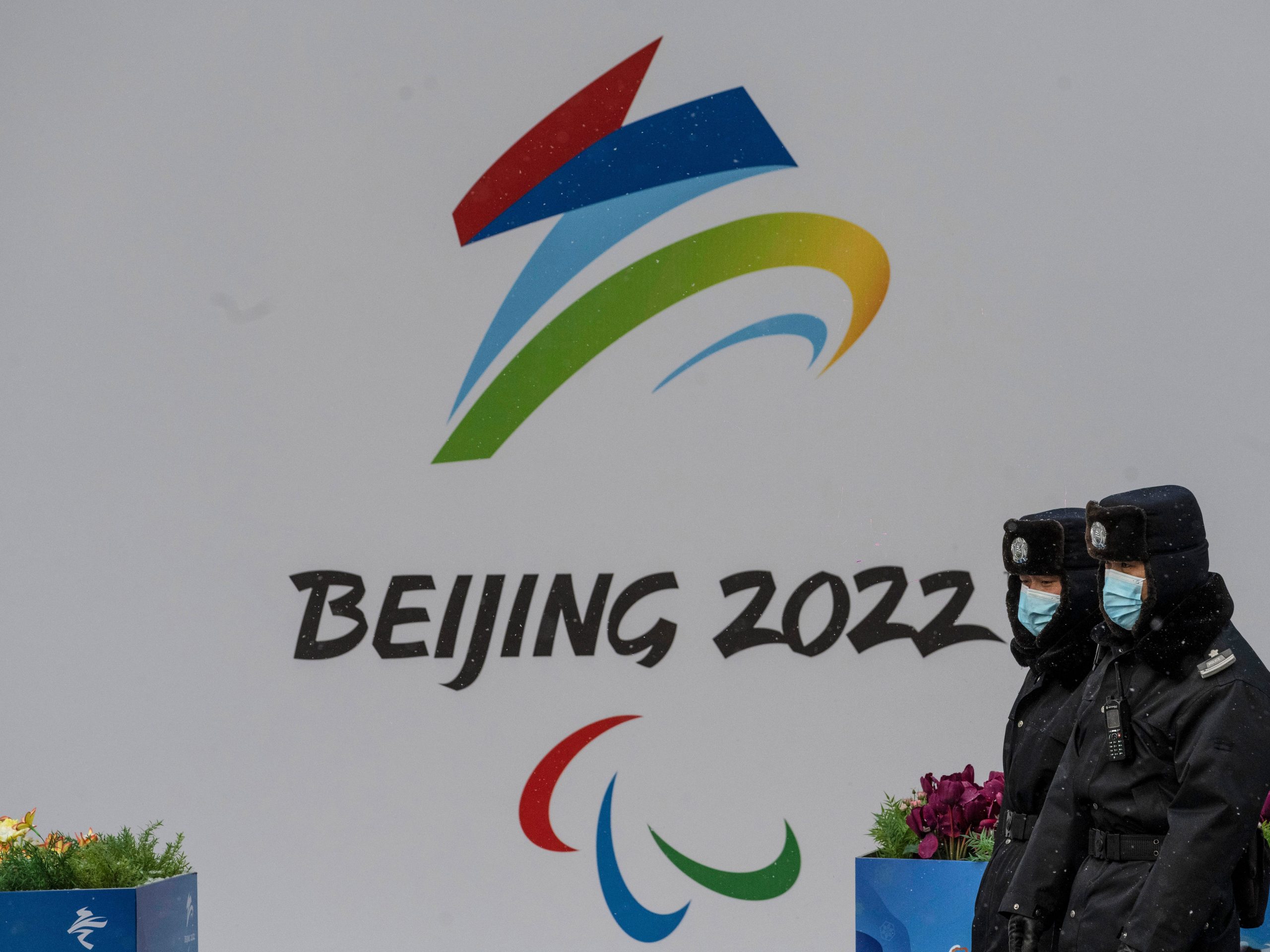 Security walk by a billboard for the Beijing 2022 Winter Olympics and Paralympics during a snowfall on January 20, 2022 in Beijing, China.