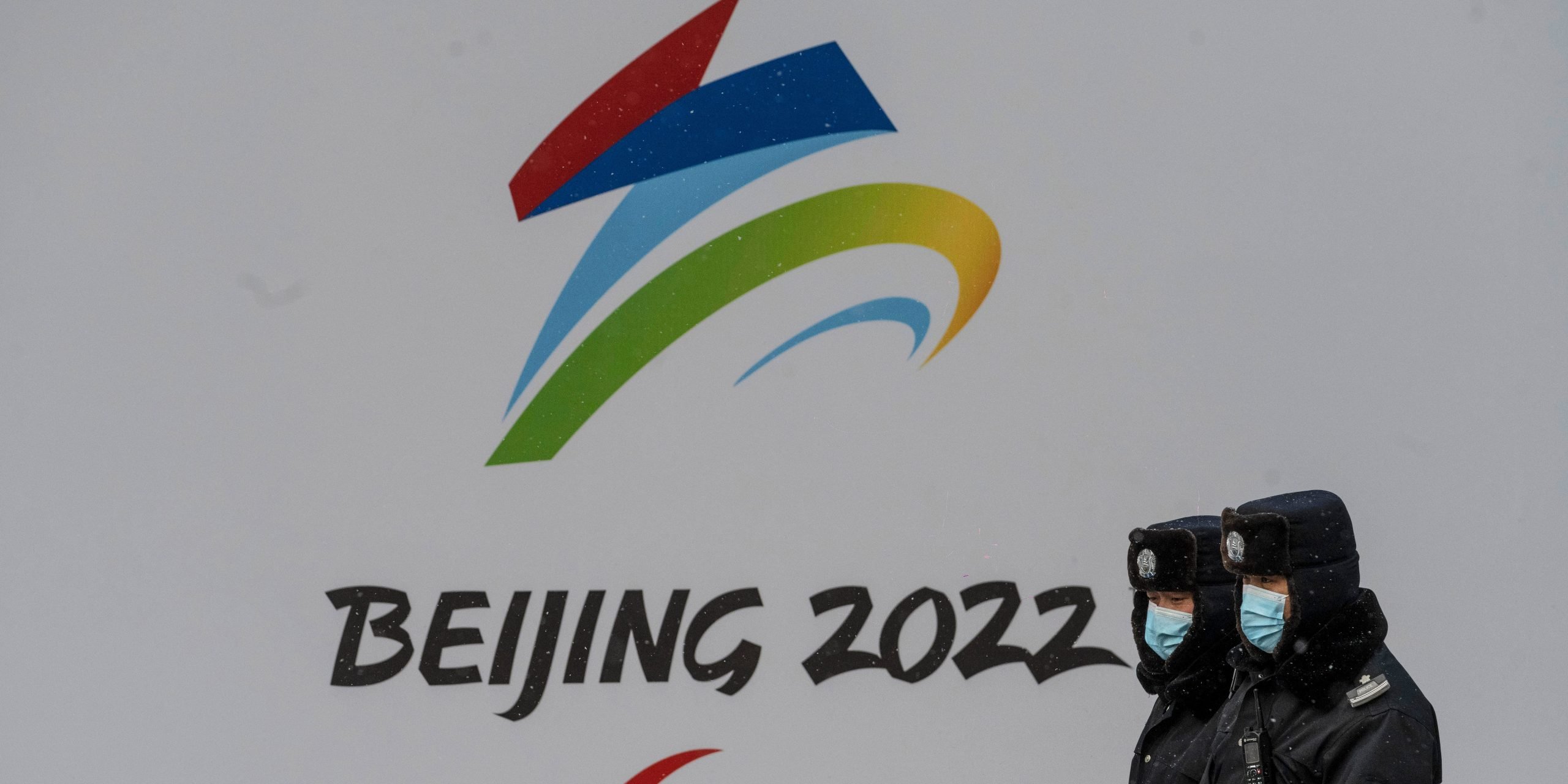 Security walk by a billboard for the Beijing 2022 Winter Olympics and Paralympics during a snowfall on January 20, 2022 in Beijing, China.