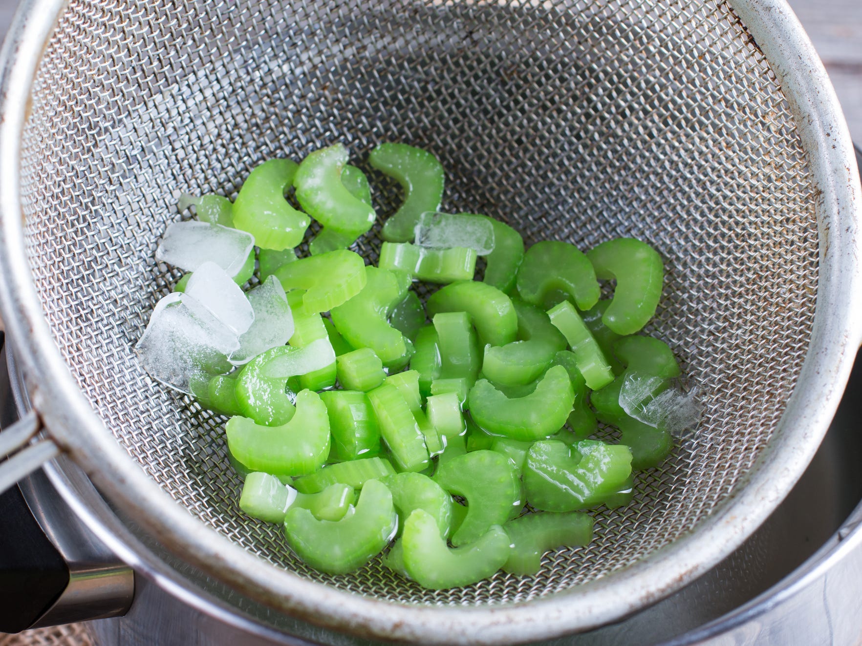Blanched celery in a strainer with some ice