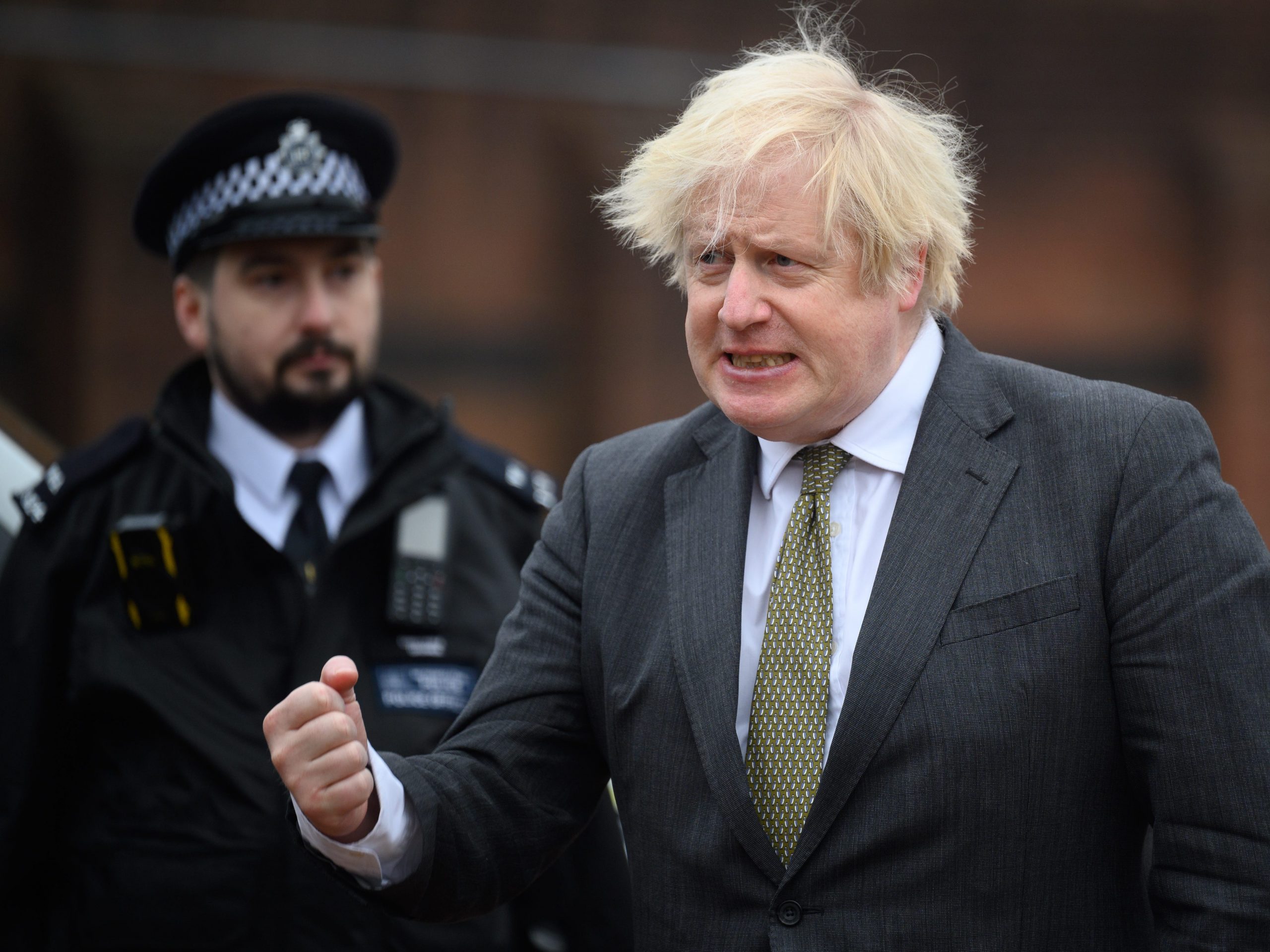 Boris Johnson at Uxbridge police station grimacing with an officer behind him
