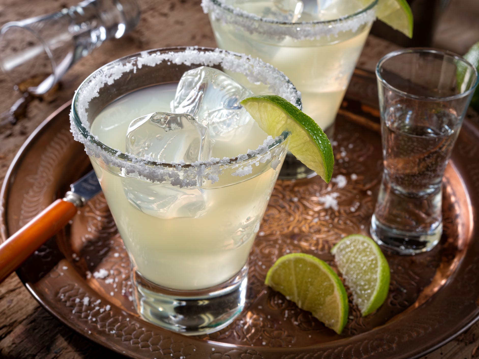 A margarita on the rocks with a salted rim, garnished with a lime wedge
