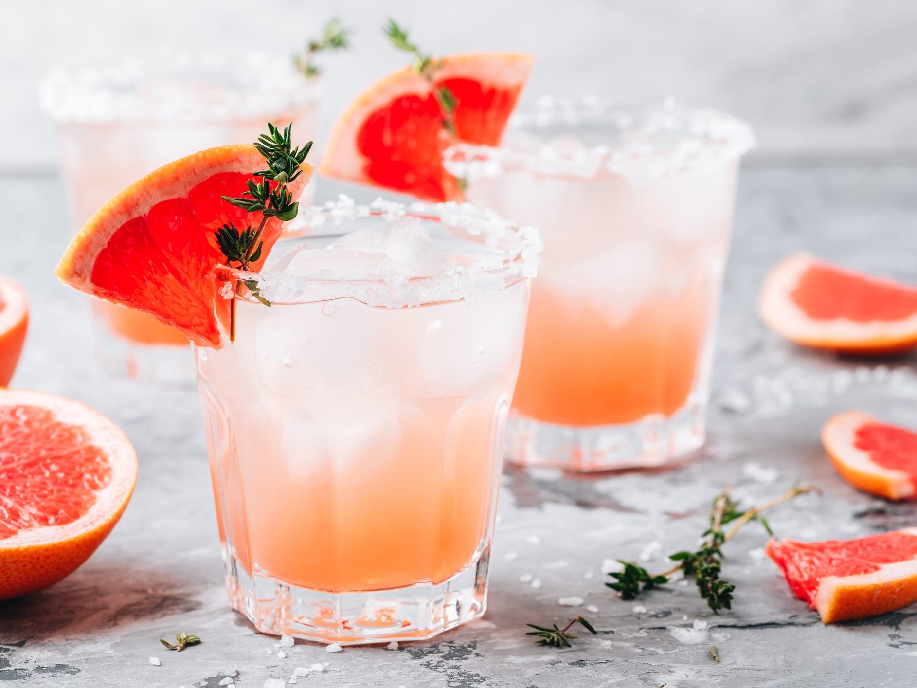 Two paloma cocktails garnished with grapefruit wedges and rosemary