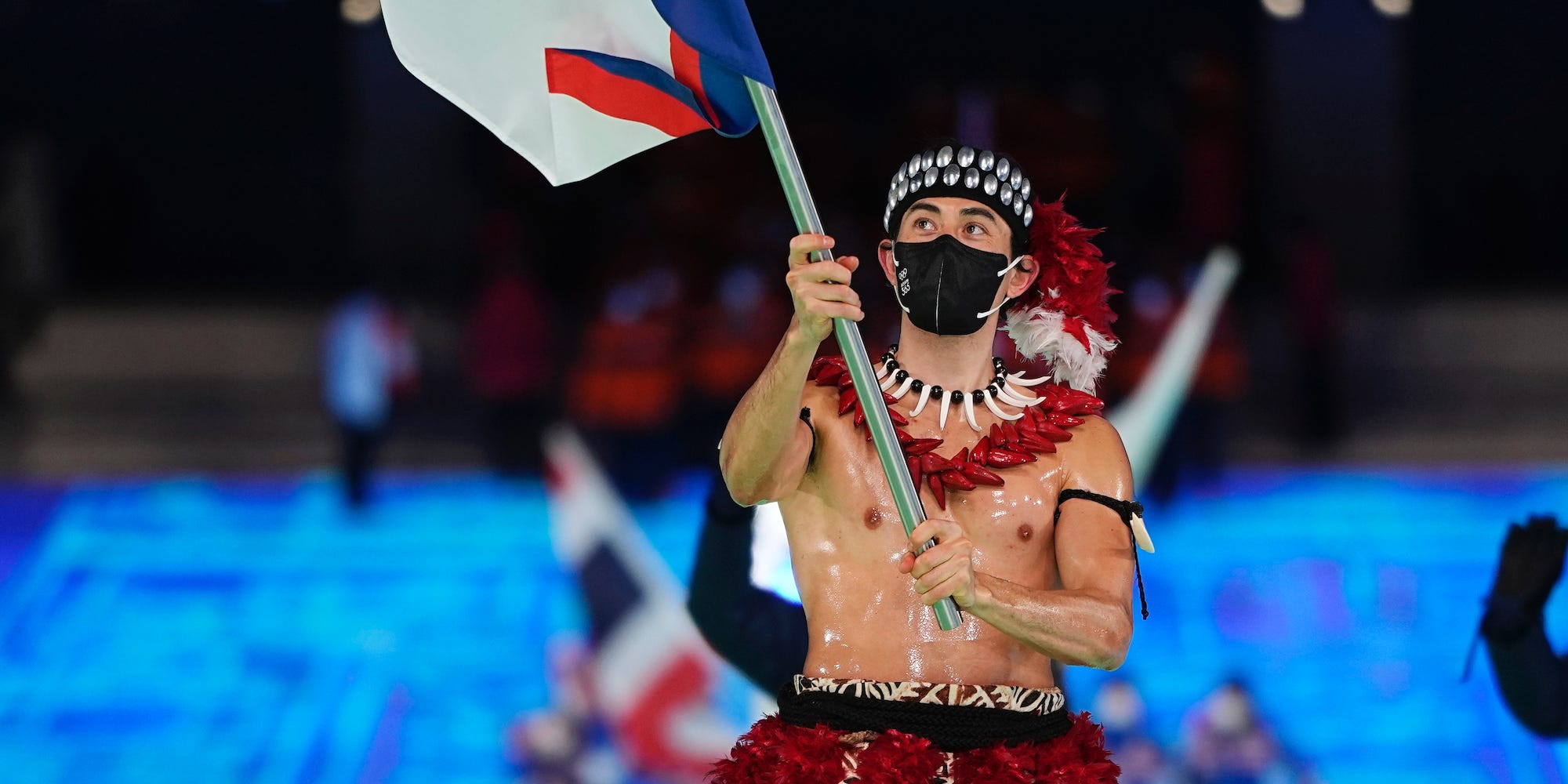 Nathan Crumpton carries the American Samoa flag at the Olympic opening ceremony while shirtless.