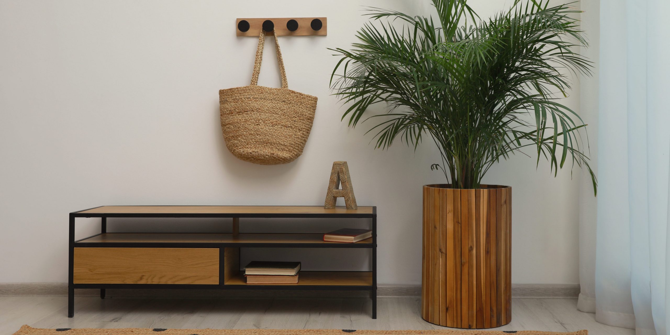 A large majesty palm in a wooden planter in the corner of a living room