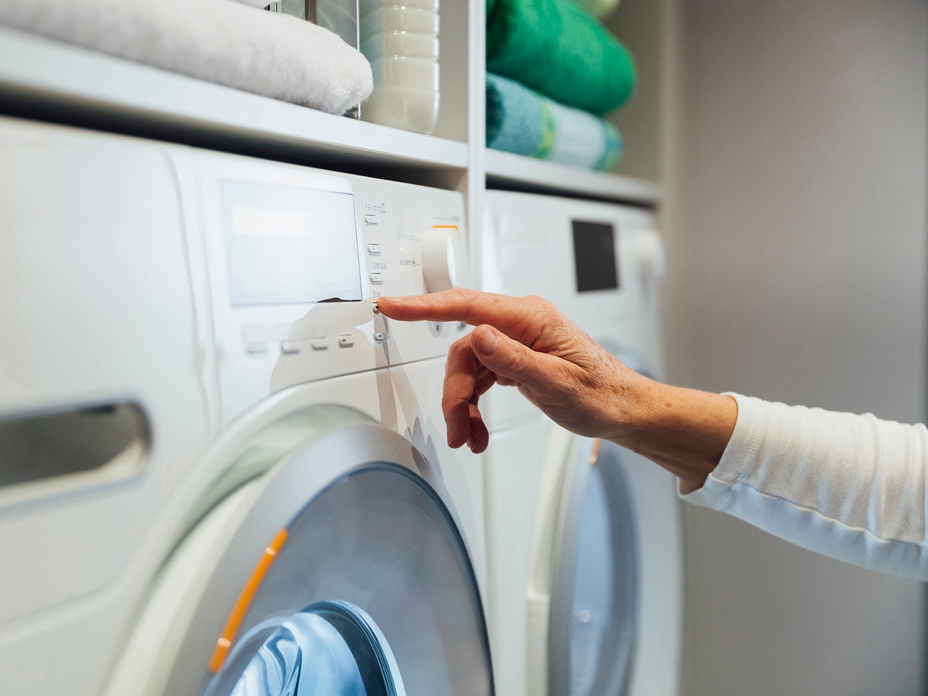 Person's handing pushing a washing machine setting button