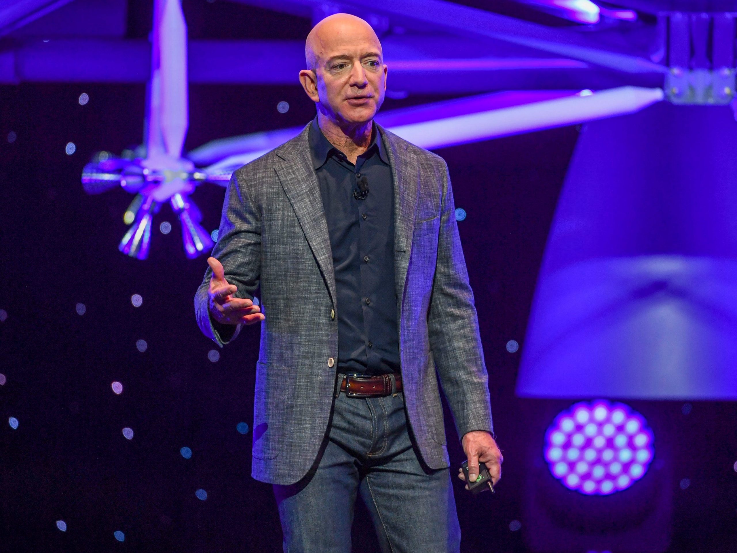 Jeff Bezos speaks with his lunar lander hovering in the background.