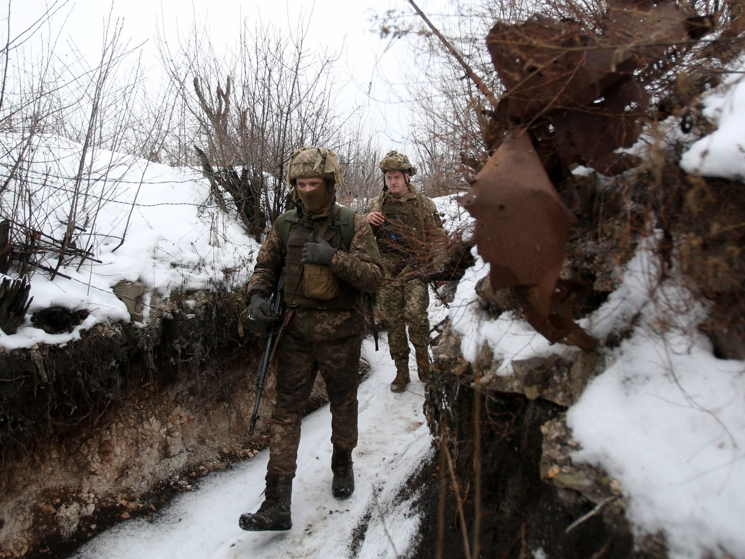 Ukrainian servicemen walk along a snow covered trench on the frontline with the Russia-backed separatists near Avdiivka, Donetsk region, on February 2, 2022.