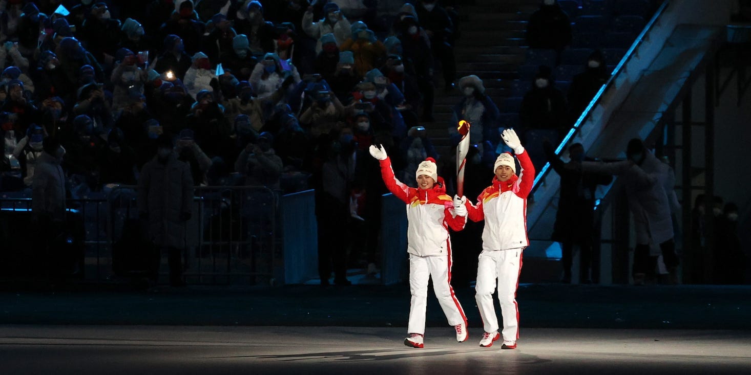 Chinese athletes Dinigeer Yilamujiang and Zhao Jiawen carry the Olympic torch at the opening ceremony of the Beijing 2022 Winter Olympic Games at the National Stadium.