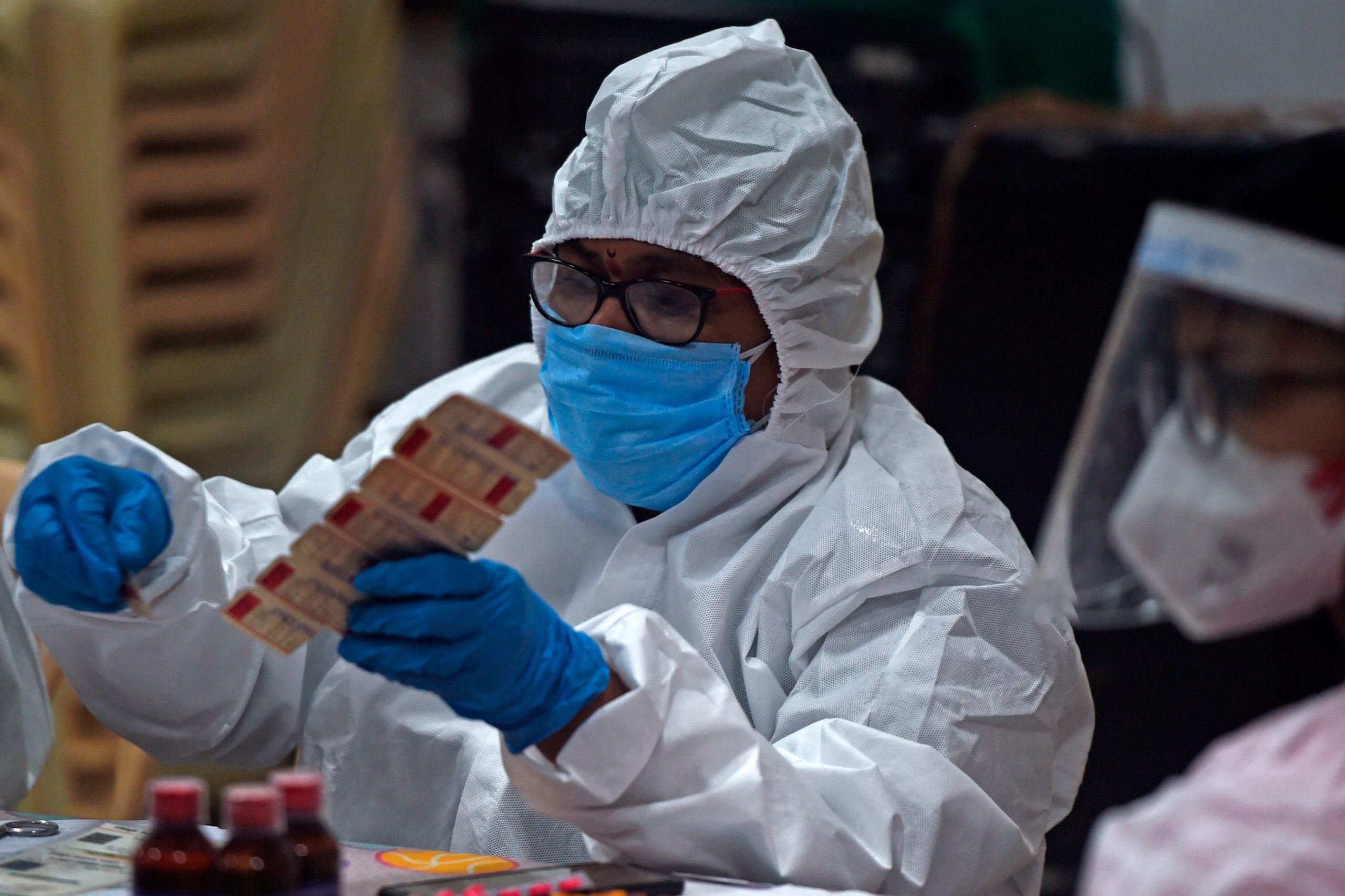 Medical volunteer distributes vitamin tablets in India, July 2020