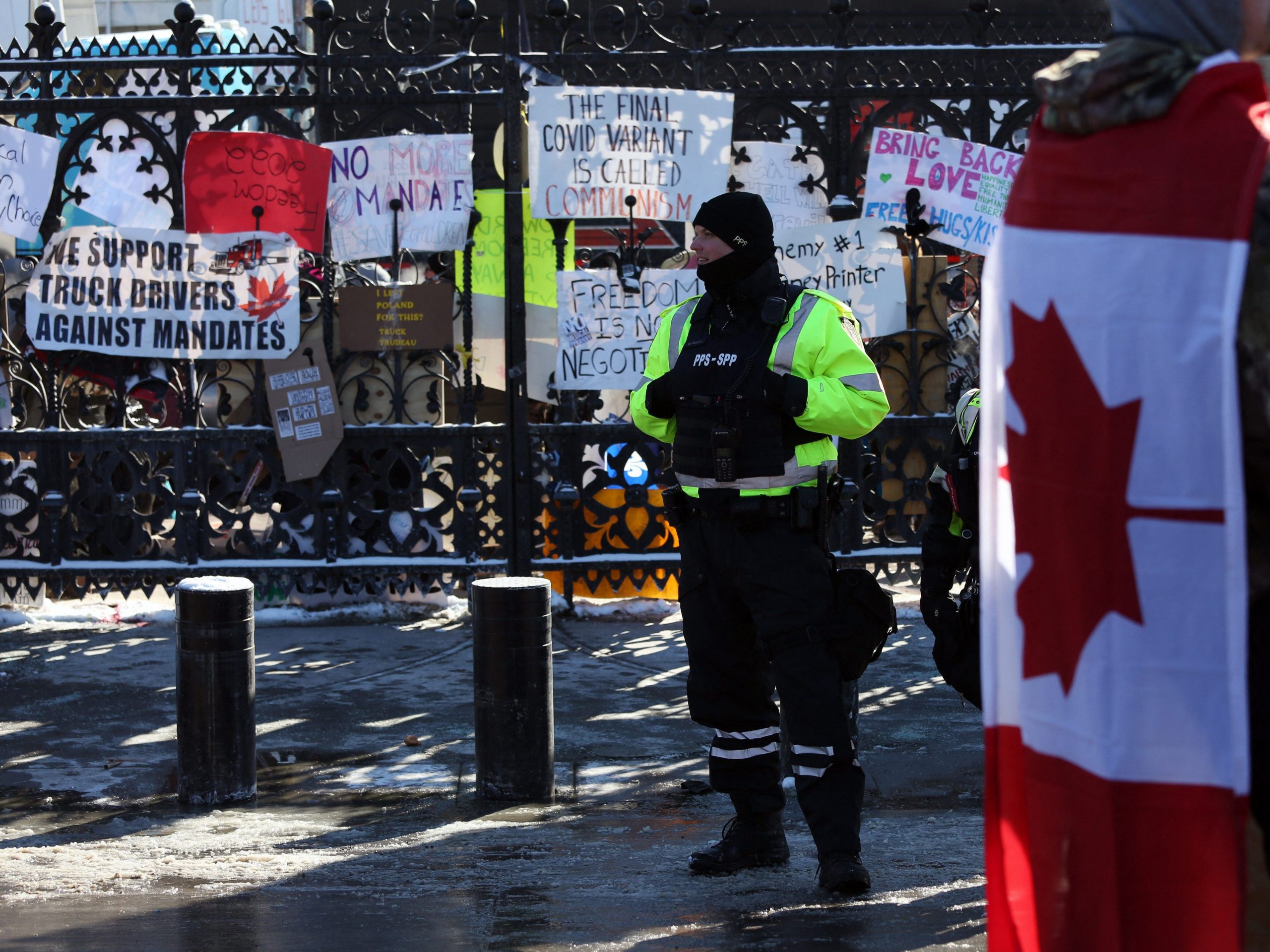 A police officer keeps watch as demonstrators against mandates and restrictions related to Covid-19 vaccines gather in Ottawa, Ontario, Canada, on February 5, 2022. - Protesters again poured into Toronto and Ottawa early on February 5 to join a convoy of truckers whose occupation of Ottawa to denounce Covid vaccine mandates is now in its second week.