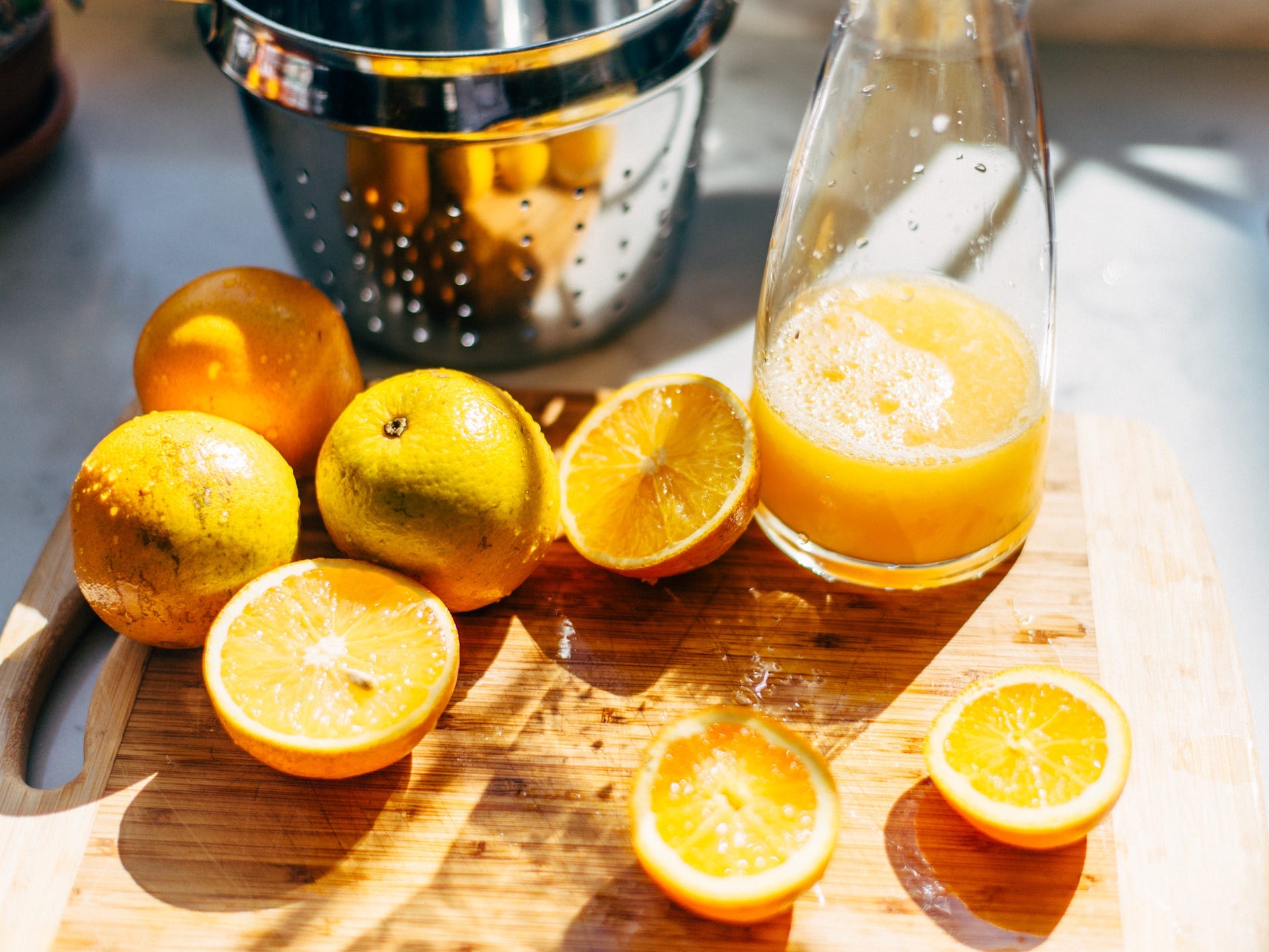 Orange halves on a cutting board next to a pitcher with orange juice in it