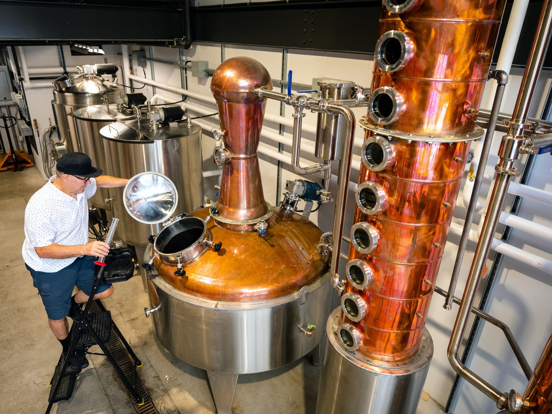 A worker at a distillery next to a large column still