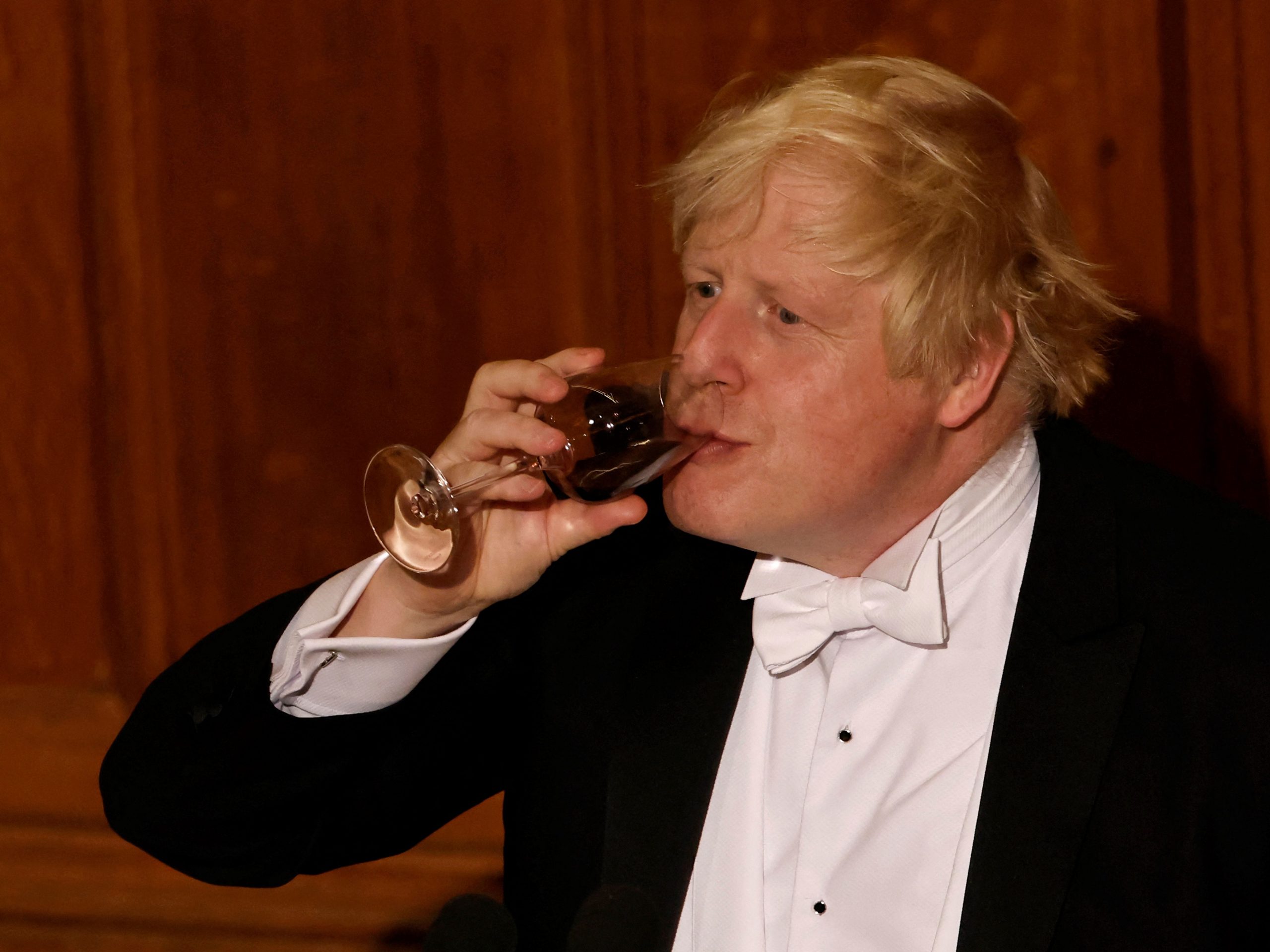Boris Johnson drinks red wine from a glass