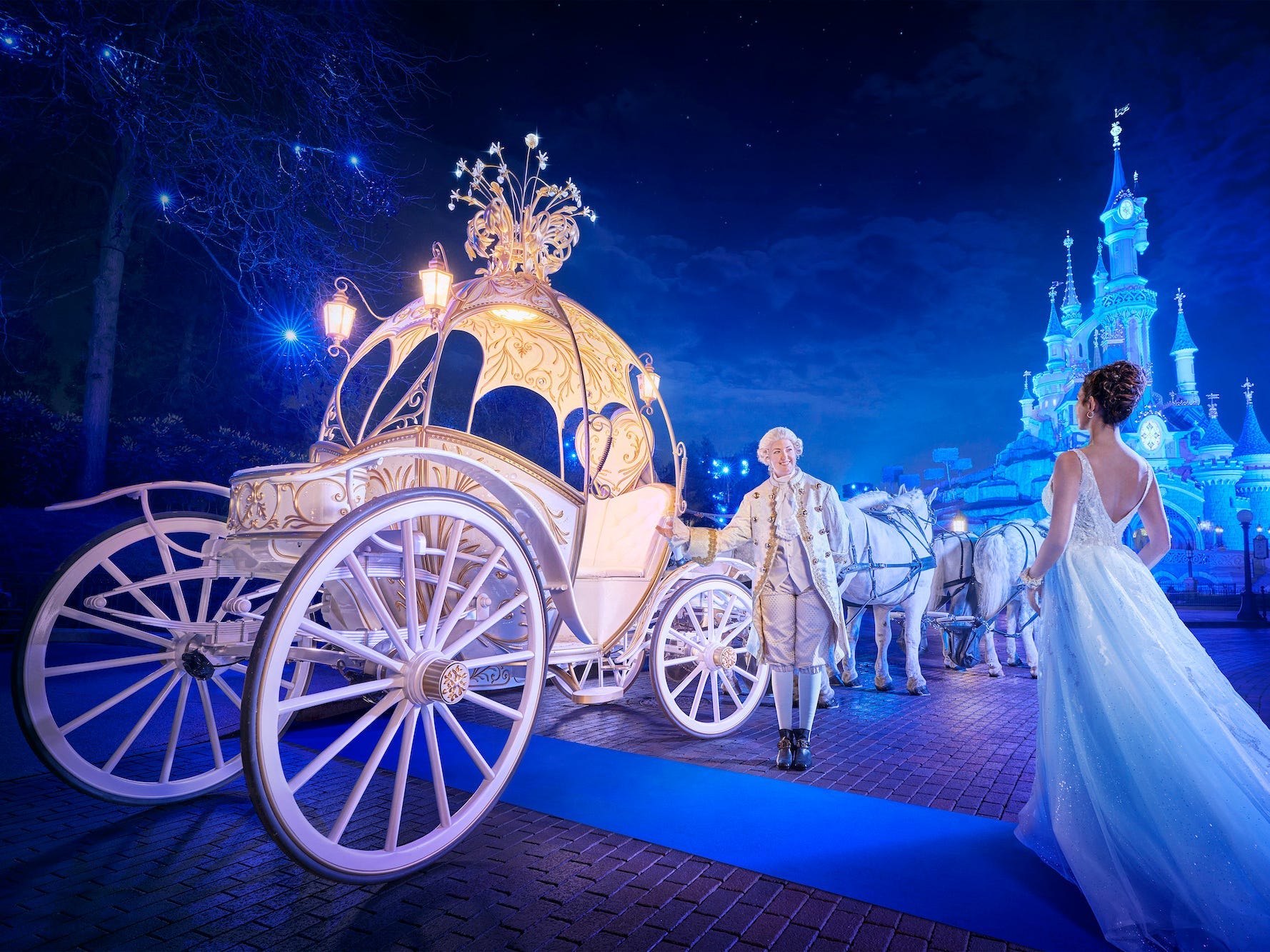 A man welcomes a woman into a carriage with a castle in the background at Disneyland Paris.