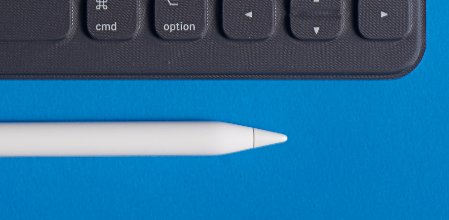 An Apple Pencil laying next to an iPad keyboard.