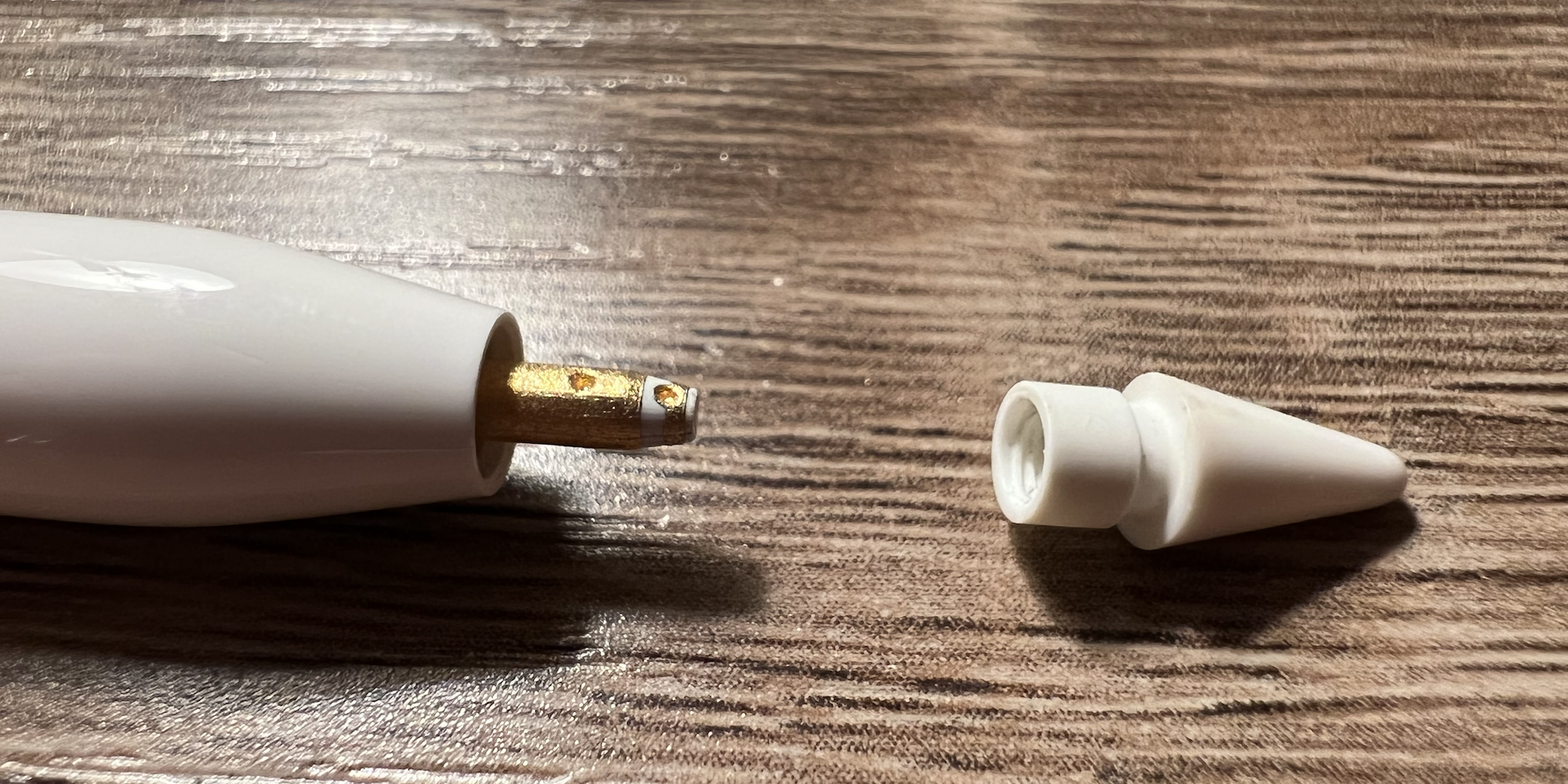 An Apple Pencil with the tip unscrewed and removed, exposing the metal underneath.