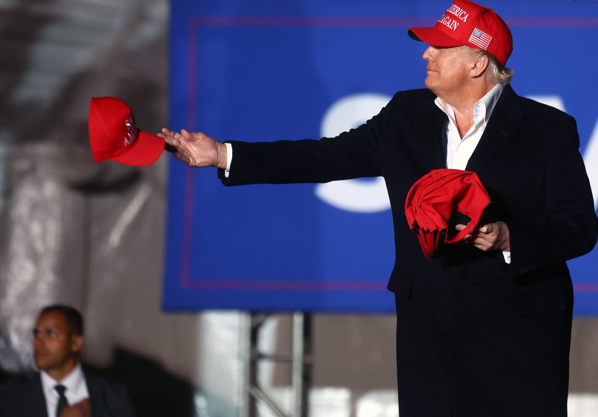 Former President Donald Trump tosses a MAGA hat into the crowd at a rally in Arizona.
