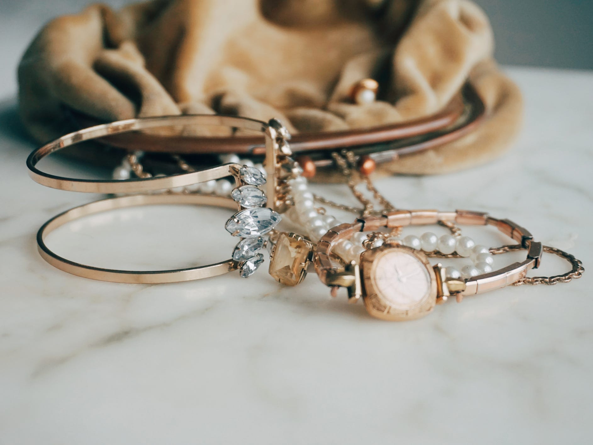 Gold jewelry in front of a bag on a countertop