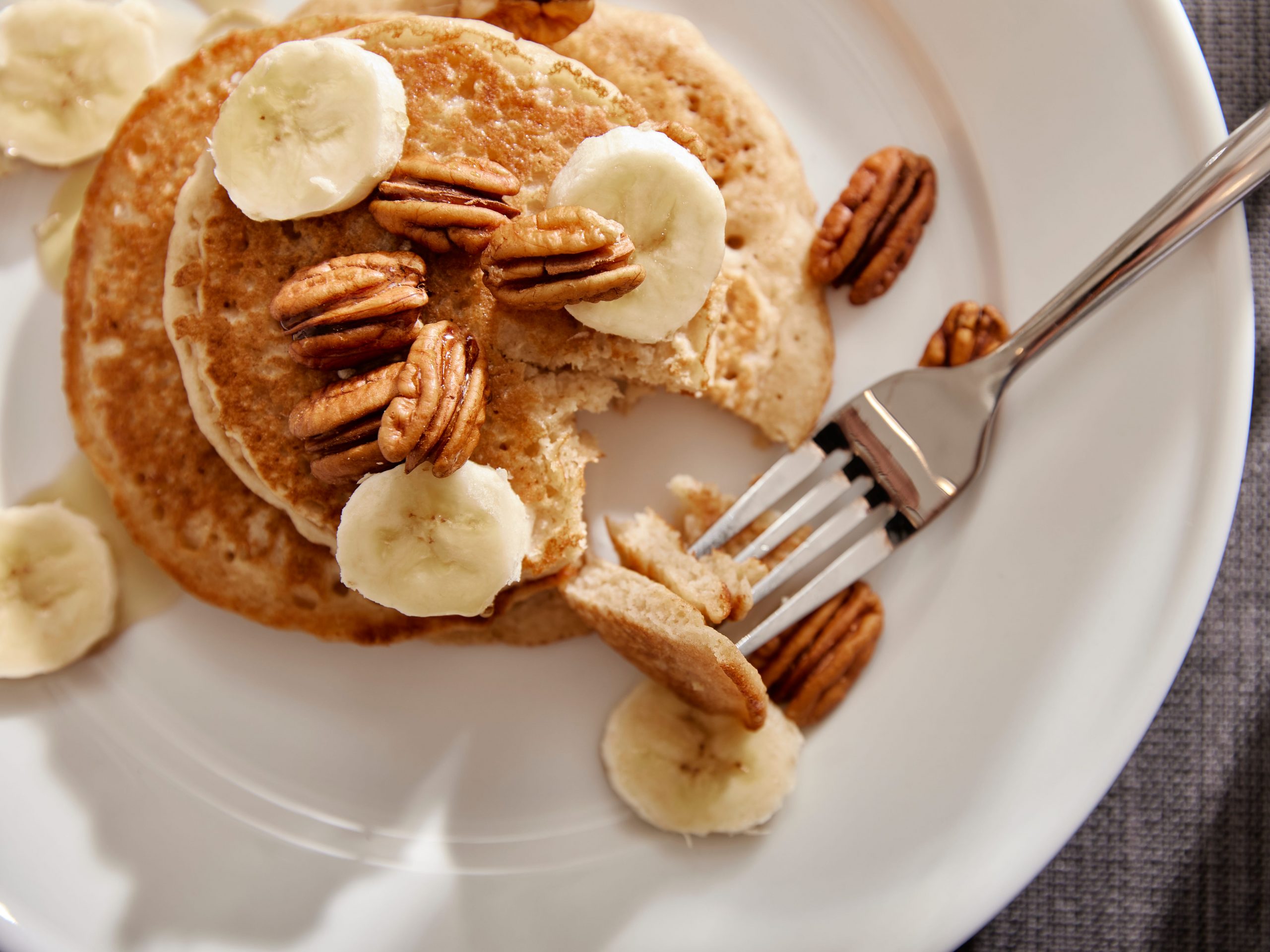 a plate of pancakes with pecans and bananas