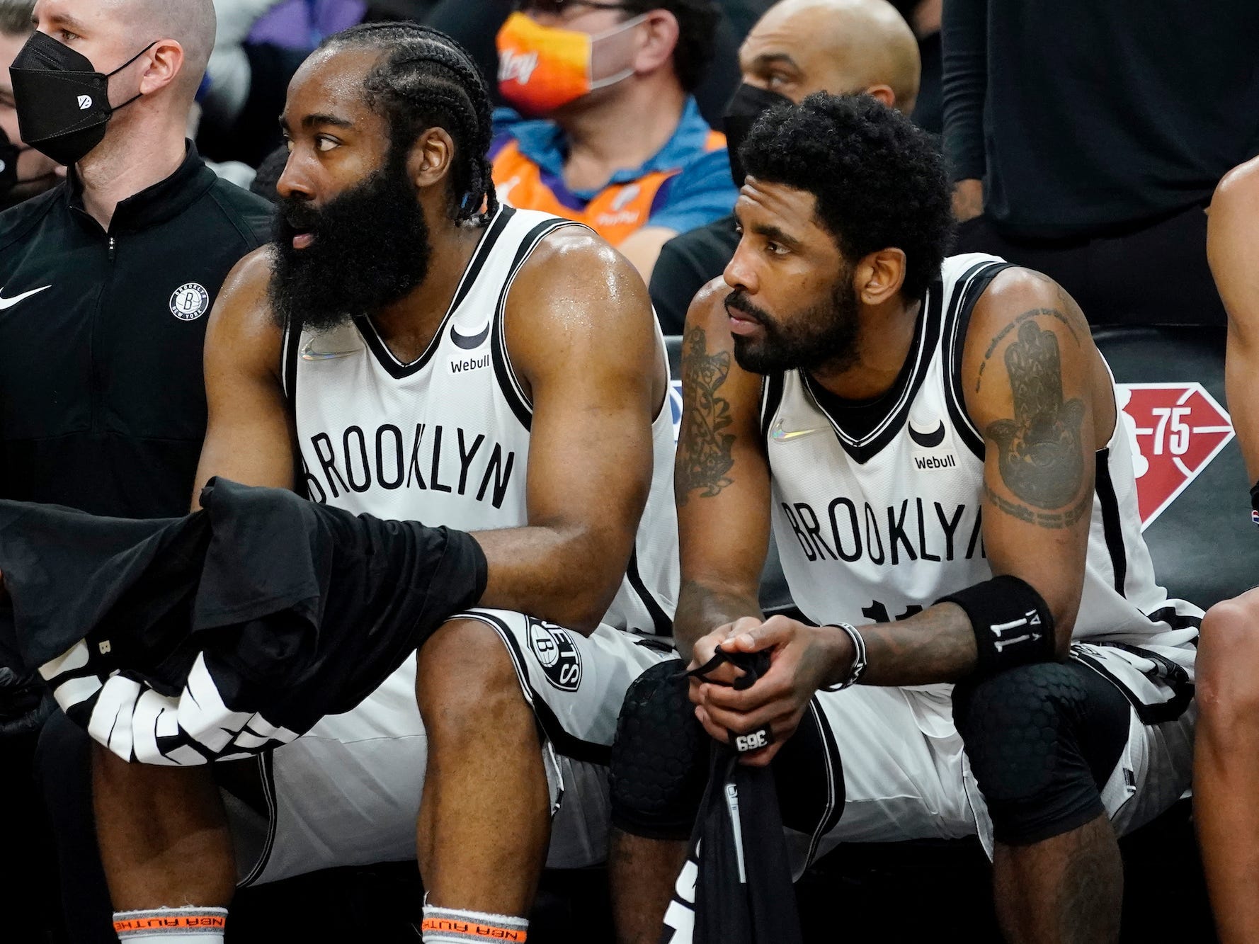 James Harden sits next to Kyrie Irving on the bench during a game in 2022.