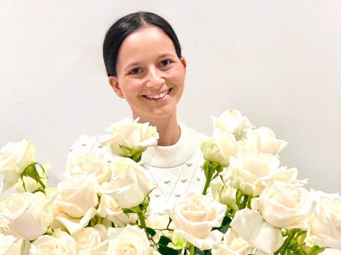 headshot of woman holding white roses