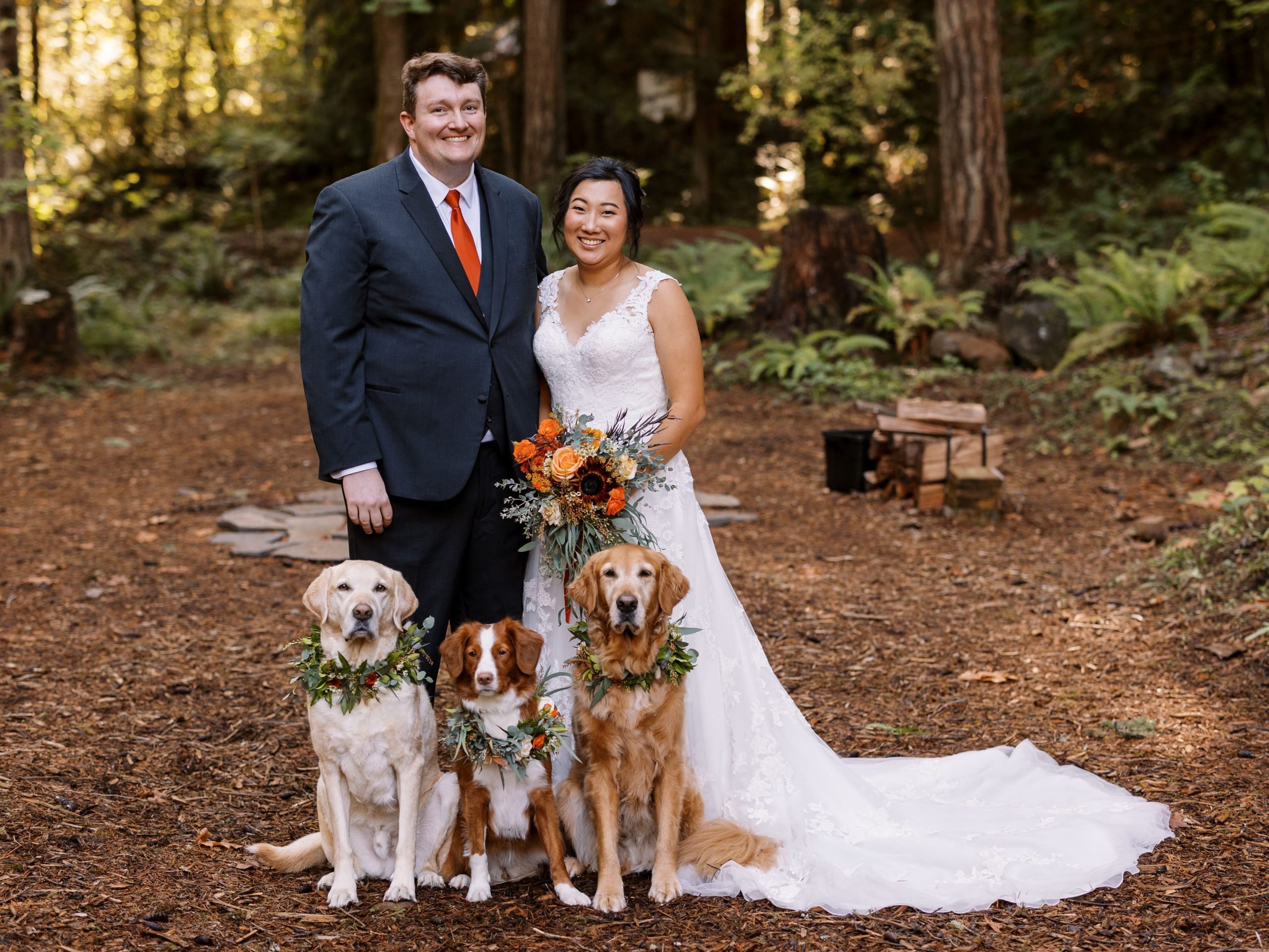 Portrait of the bride and groom and their three dogs wearing wreath necklaces.