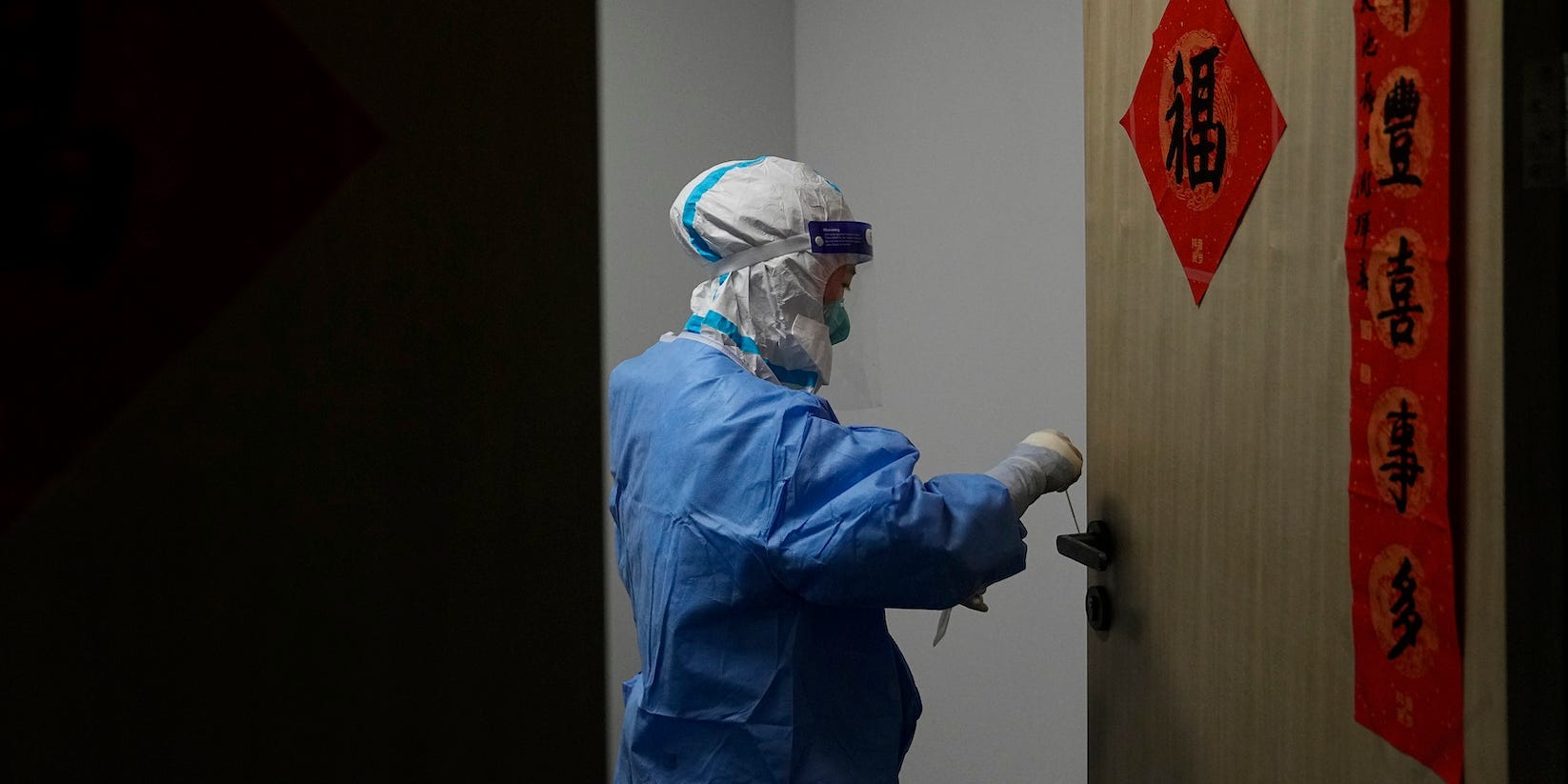 A medical worker collects a sample from a door knob of an office to test for COVID-19 in the main media center at the 2022 Winter Olympics, Friday, Feb. 11, 2022, in Beijing.