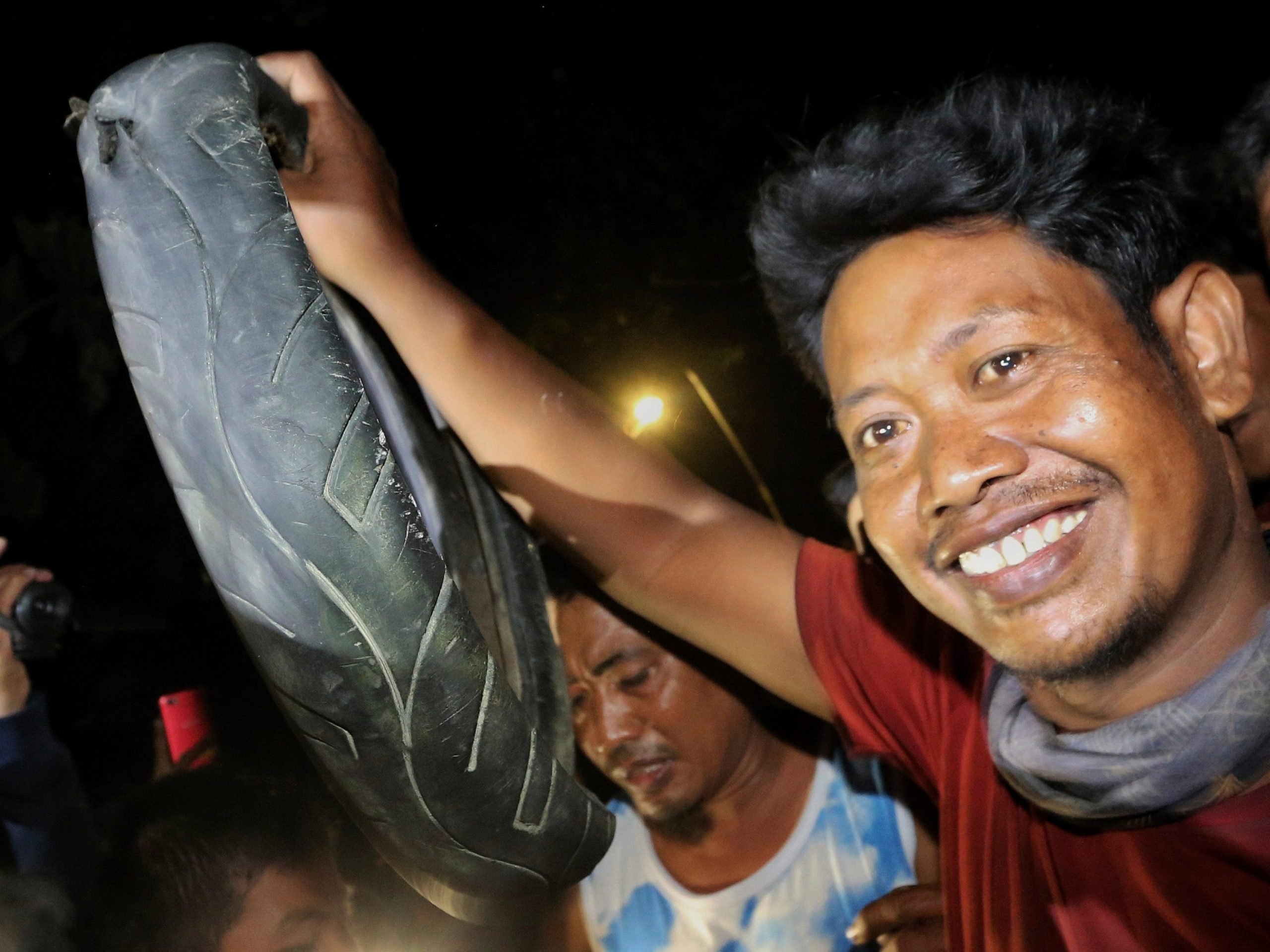 Tili, a bird catcher, holds the tire after removing it from around the neck of a crocodile.