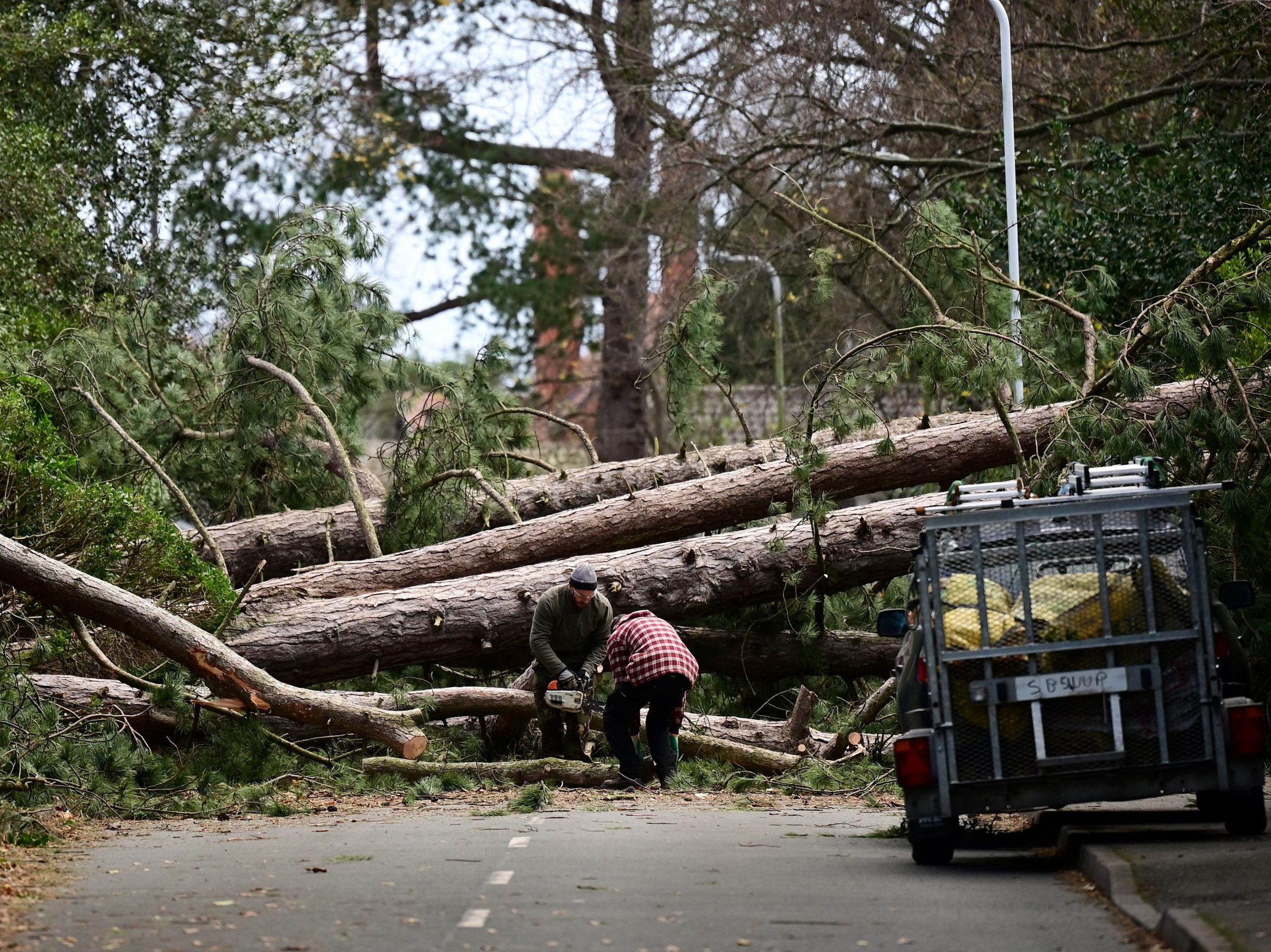 Residents clear branches from a fallen tree in Birkenhead, north west England on November 27, 2021, as "Storm Arwen" triggered a rare "red weather" warning.