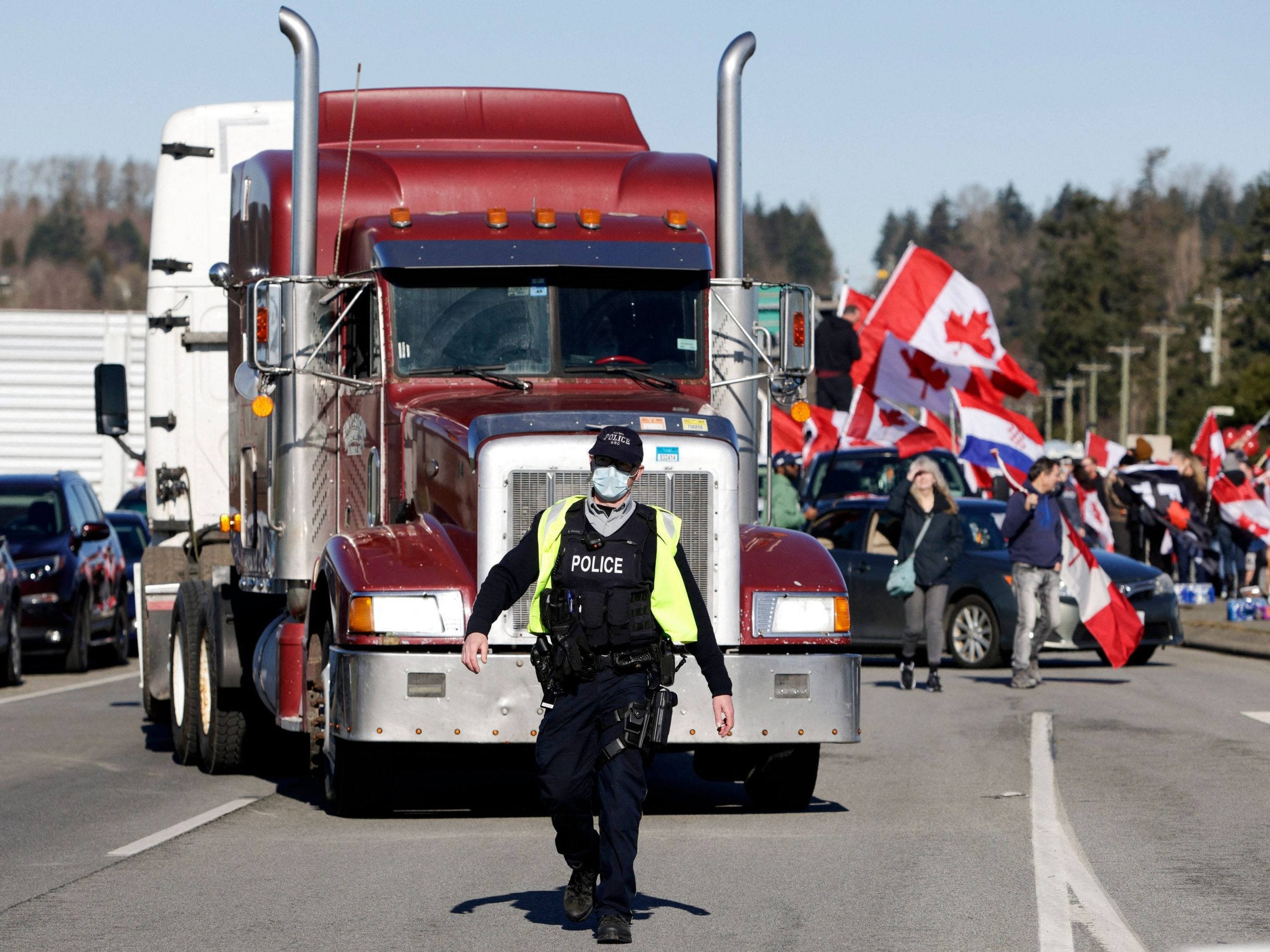 An Royal Canadian Mounted Police (RCMP) officer directs a truck through congestion as anti-vaccine mandate protesters demonstrate on Highway 15 near the Pacific Highway Border Crossing on the US-Canada border in Surrey, British Columbia on February 12, 2022.