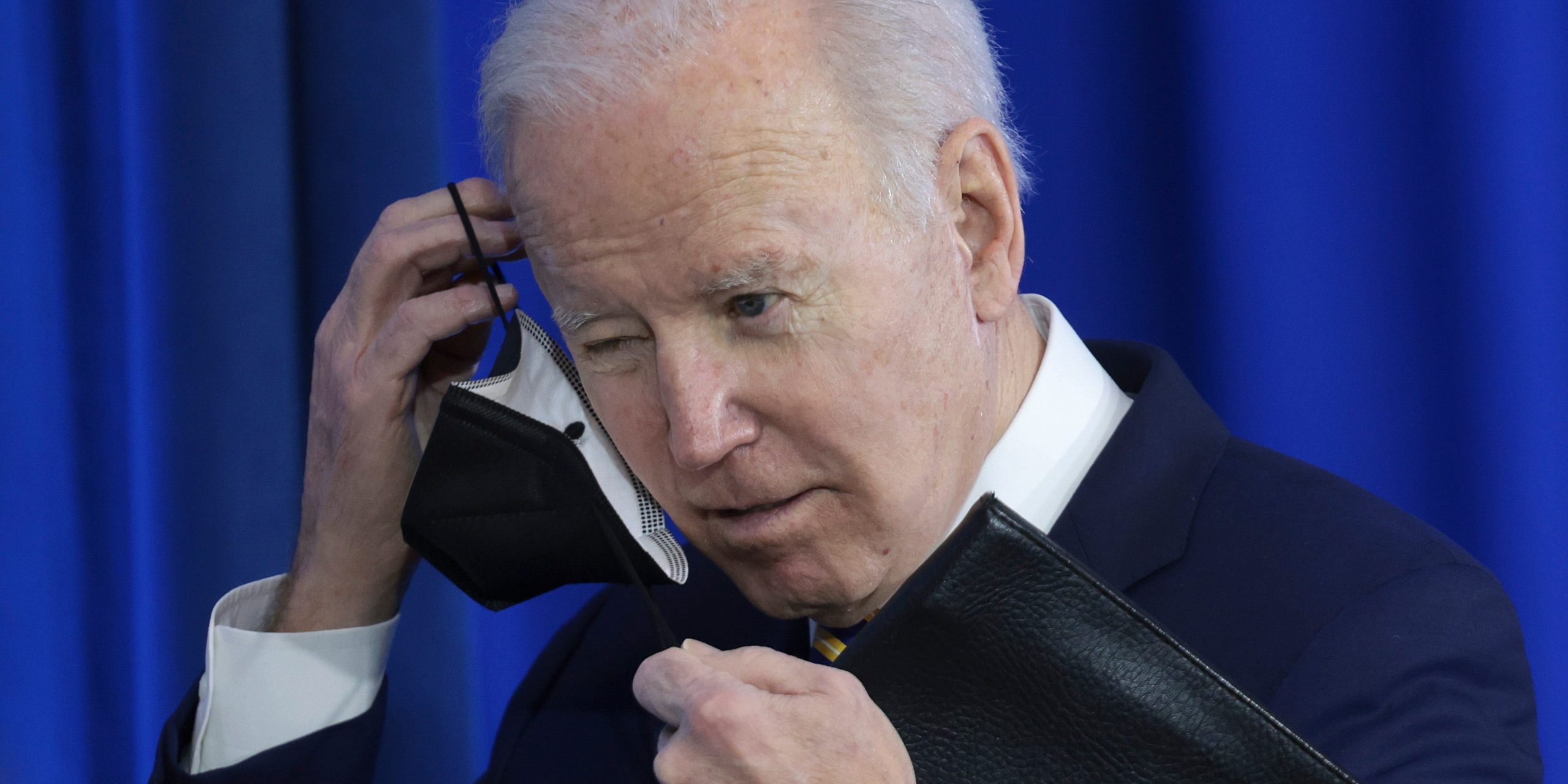 Joe Biden removes his mask before speaking at an event.