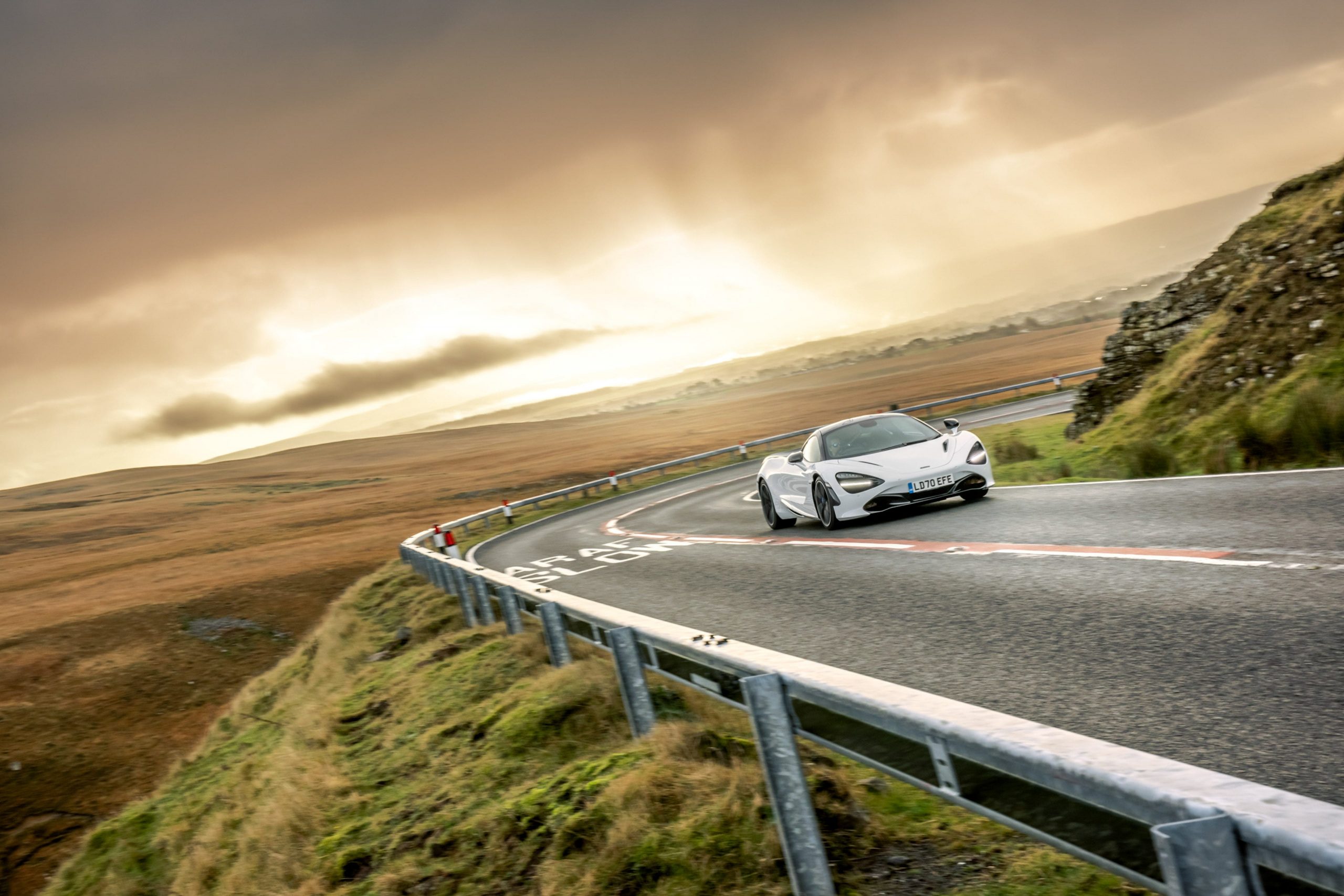 A white McLaren 720S on a mountainside road.