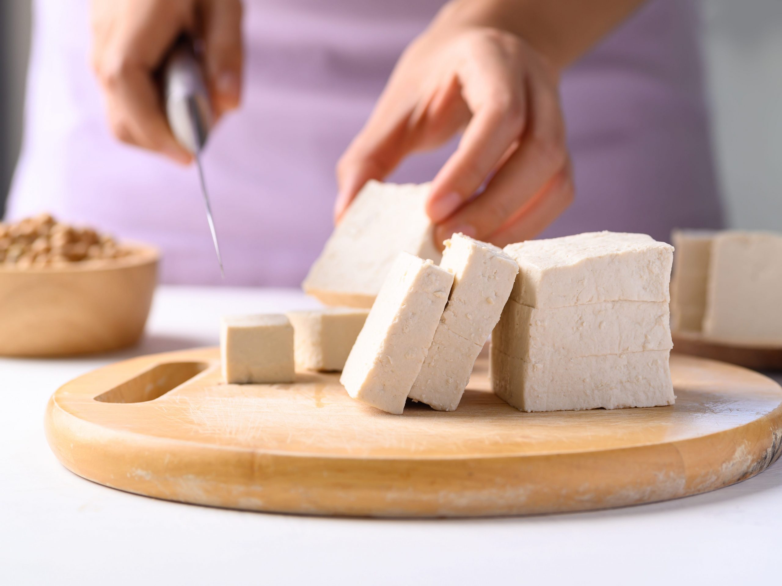 Person cutting tofu on a cutting board