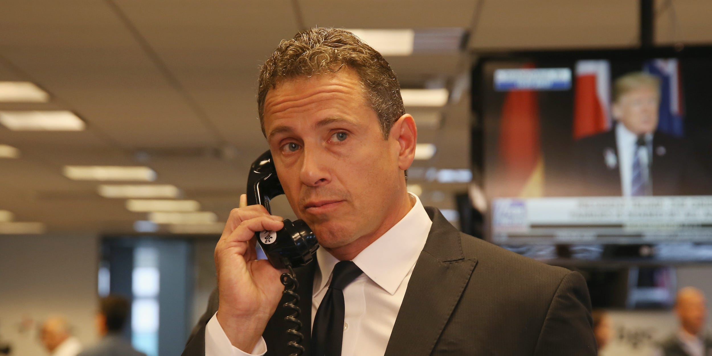 Chris Cuomo holds a landline phone to his ear, looking off to his left.