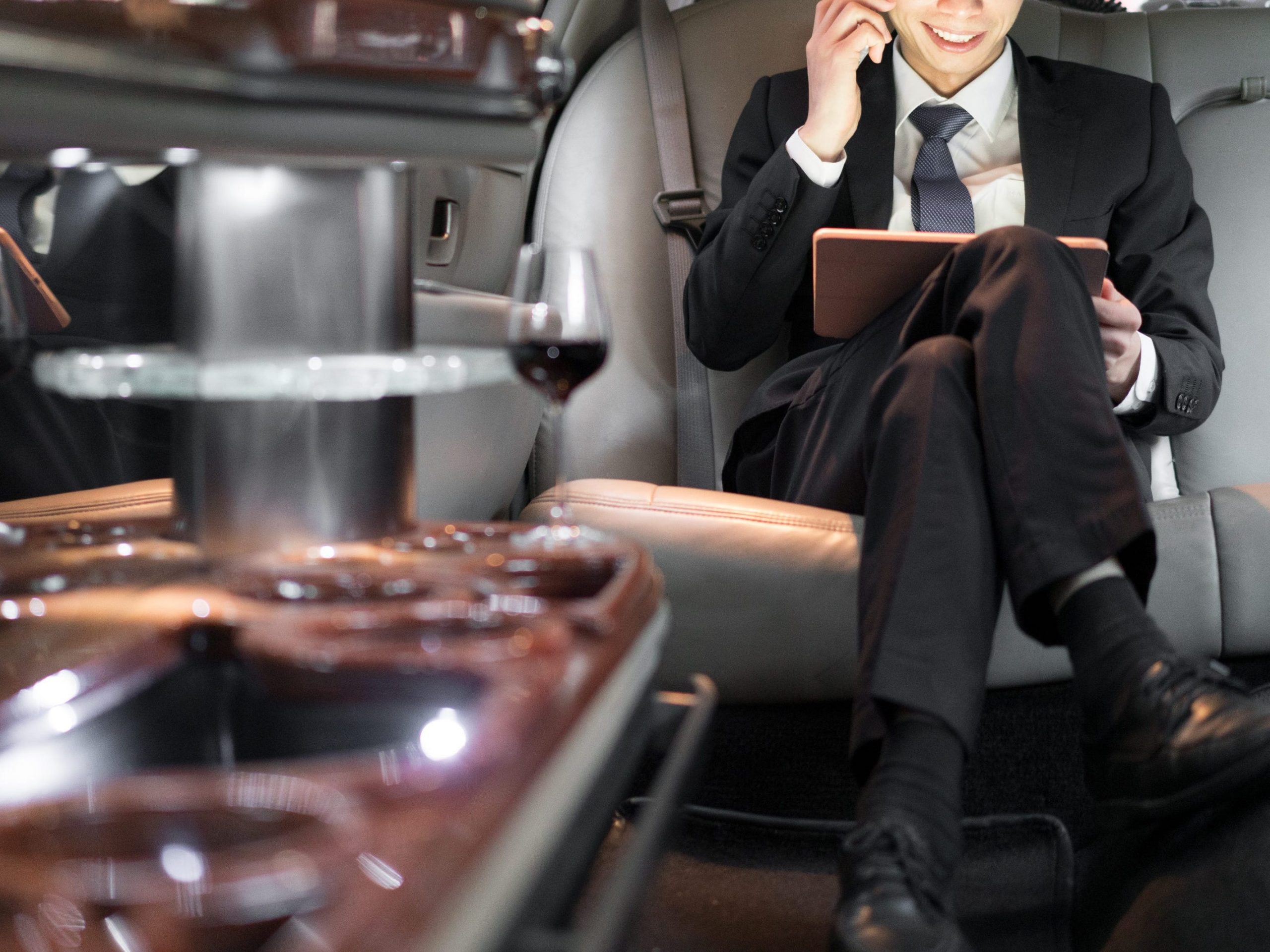 An Asian businessman uses a tablet in a limo.