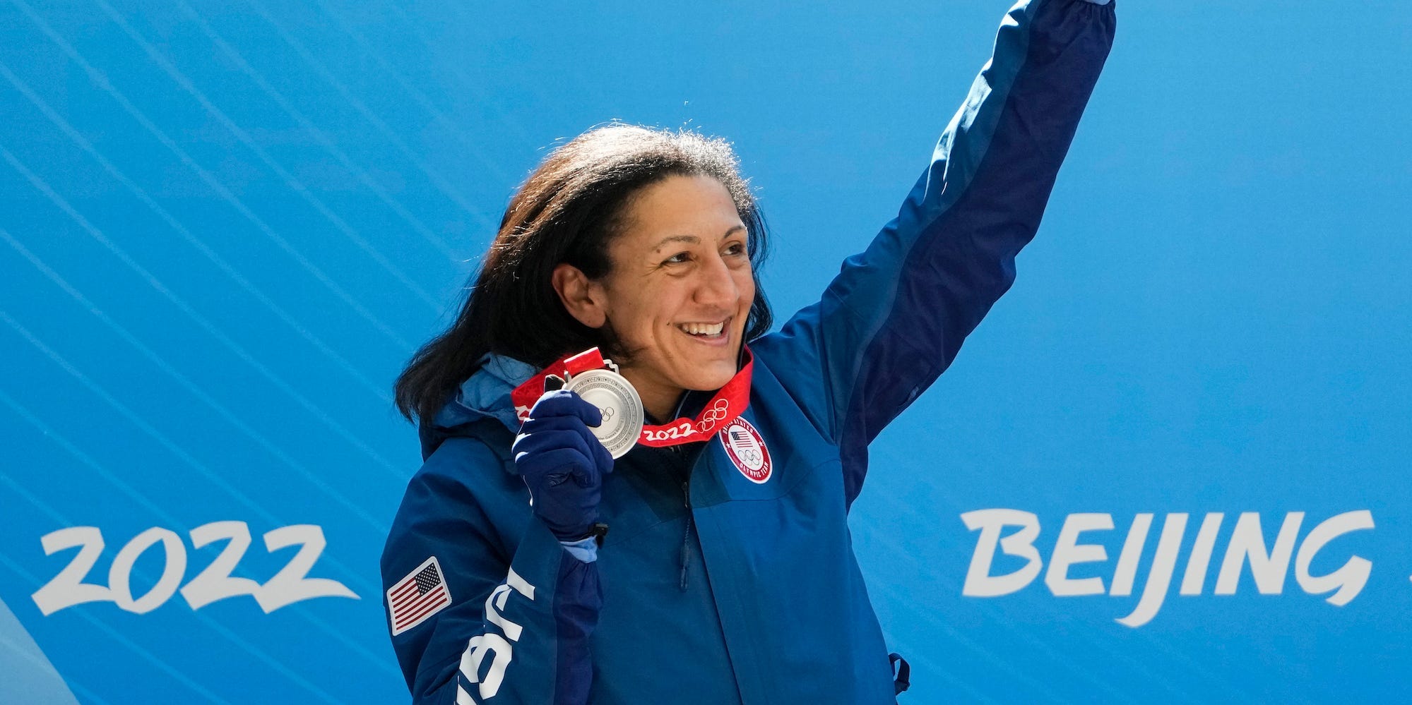 Elana Meyers Taylor holds up her silver medal in celebration at the Beijing Olympics.