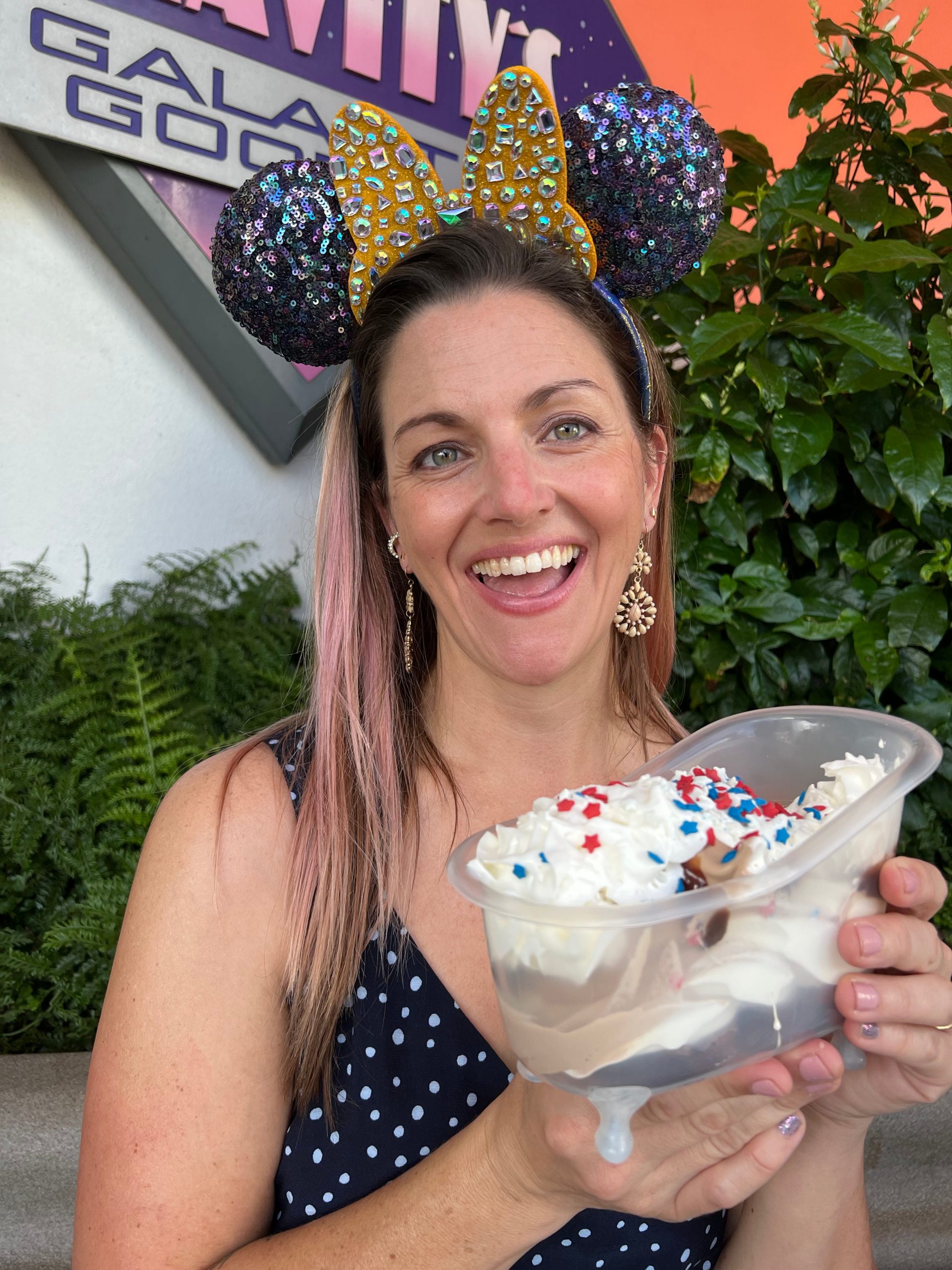 The author, Tarah Chieffi, wearing blue and gold mouse ears and holding the white sundae.