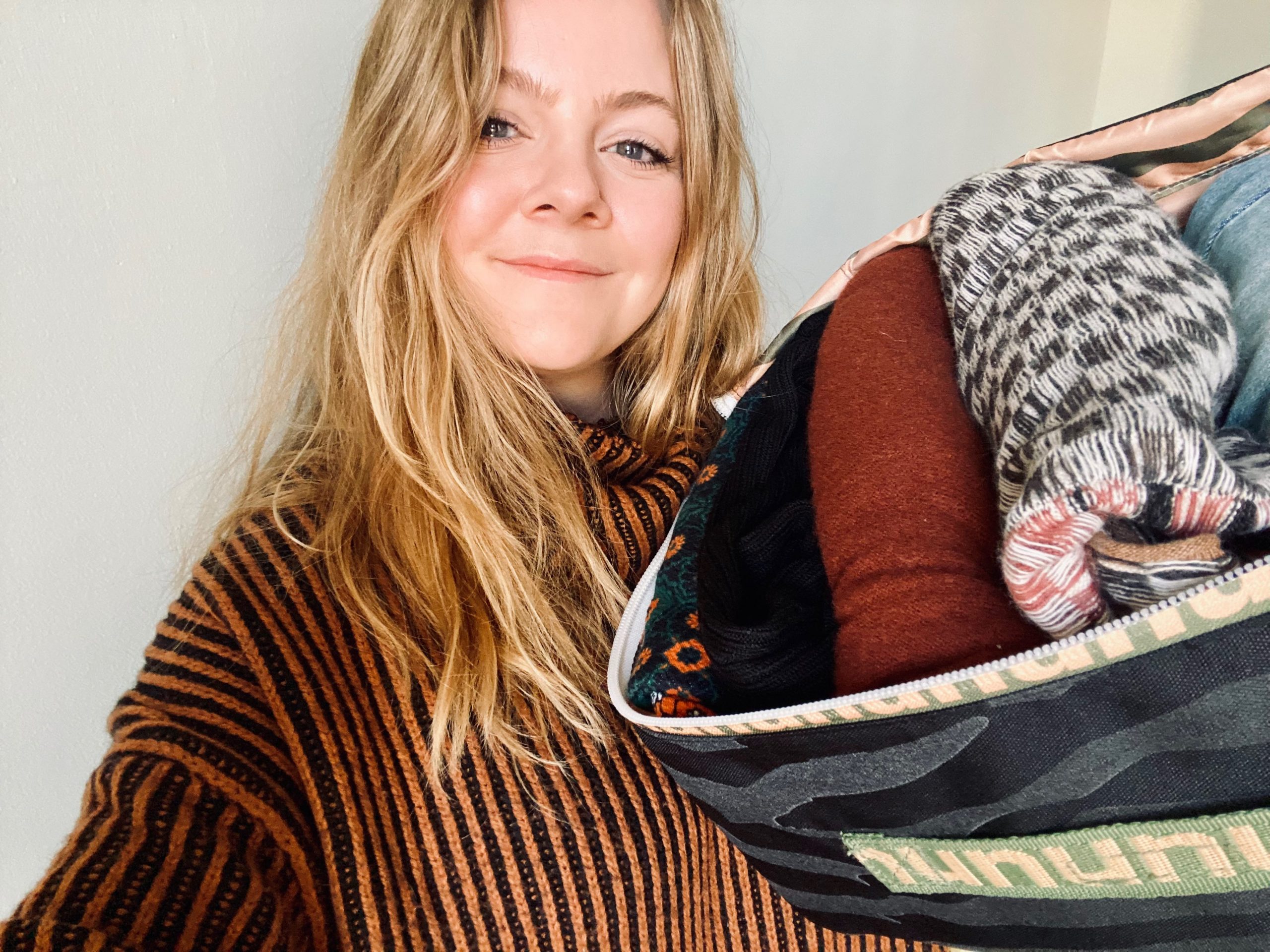 Woman holds bag with rented folded clothing from Nuuly