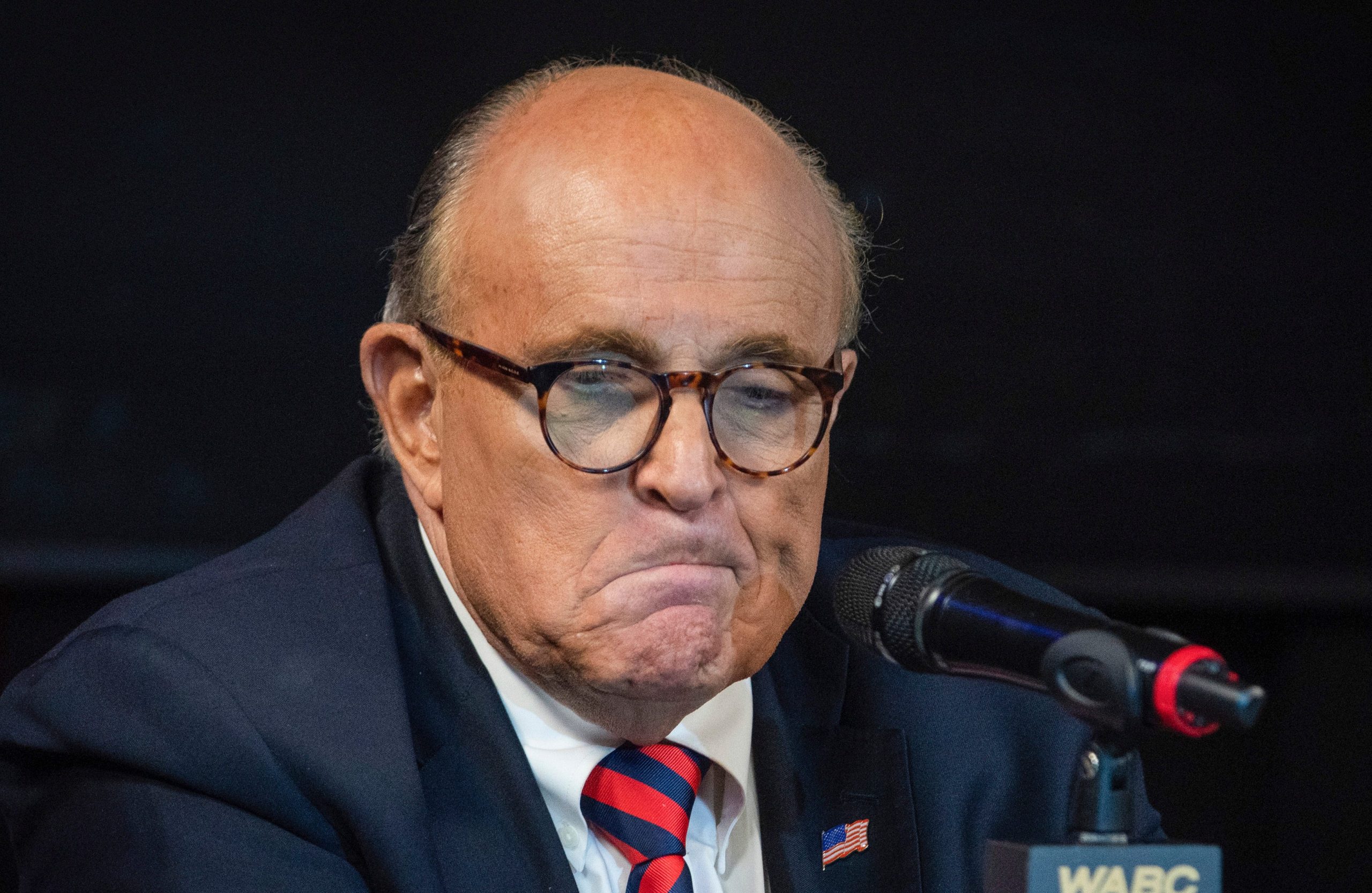 Former New York City Mayor Rudy Giuliani twists his mouth in a reaction while on a talk show