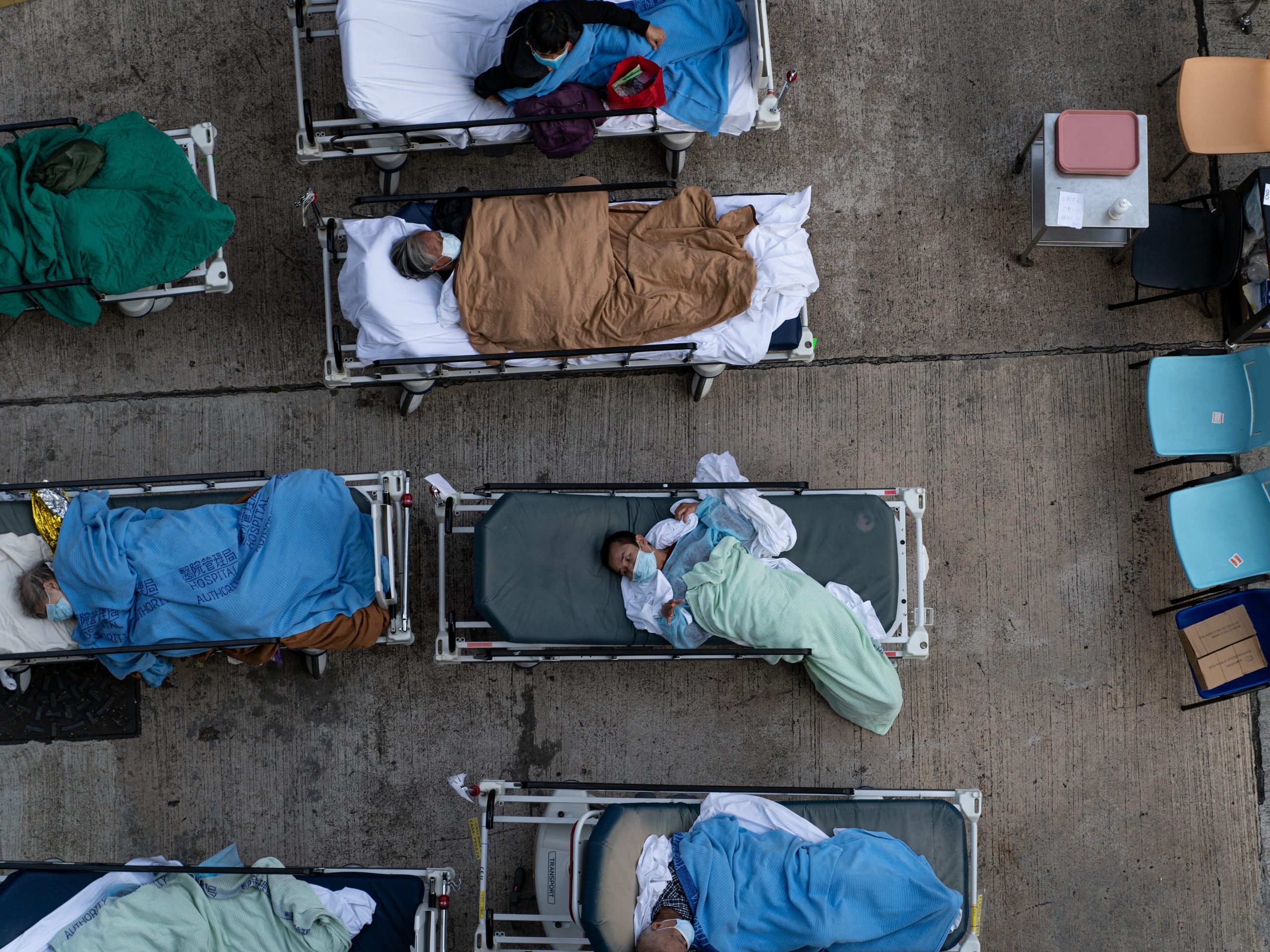 On February 16, 2022, a patient lies in a hospital bed waiting for medical treatment in a temporary shelter outside the Caritas Medical Center in Hong Kong, China, while medical staff take care of the patient.