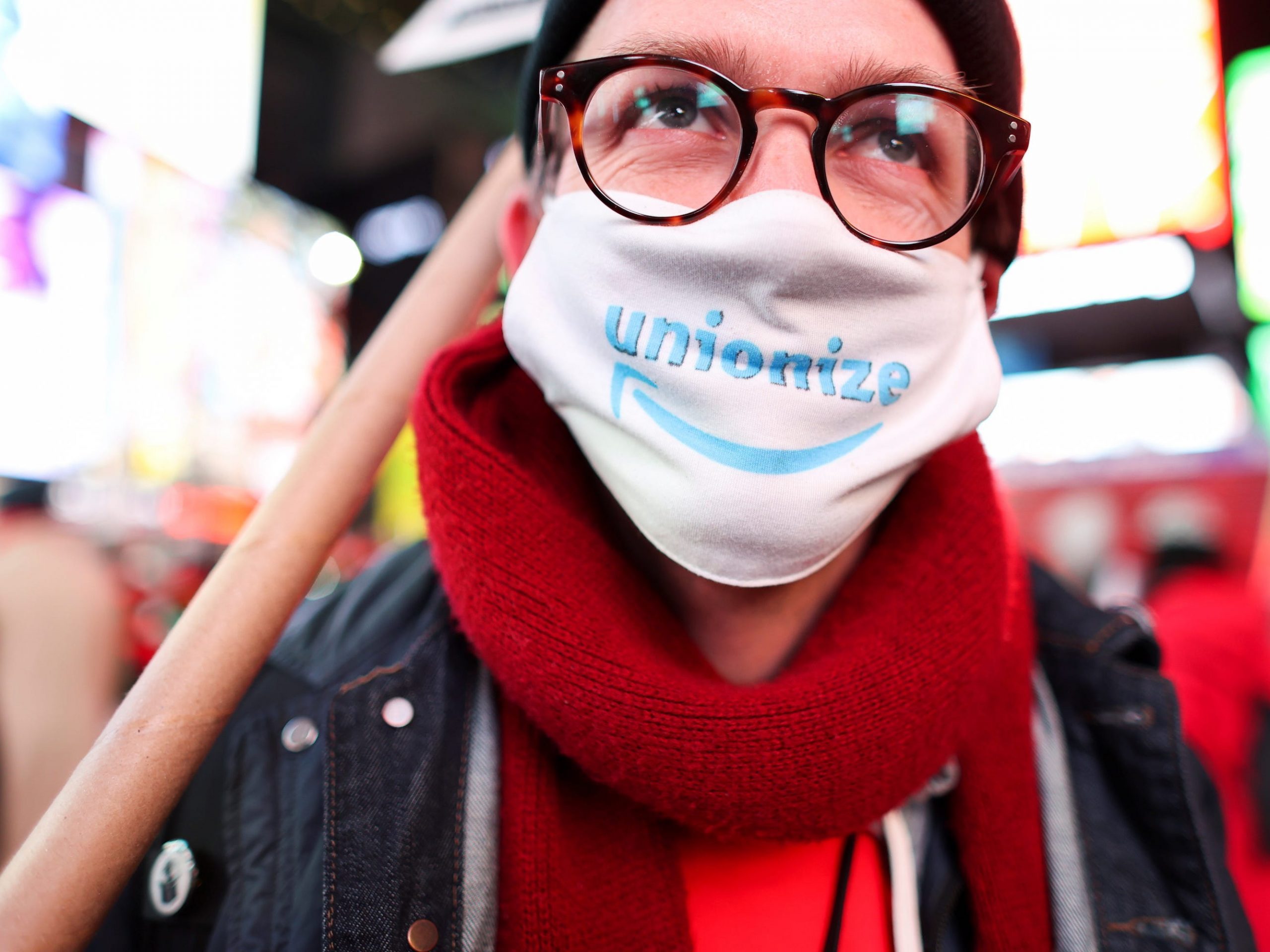 A protestor wears a mask that says "unionize" with the Amazon smile logo on it.