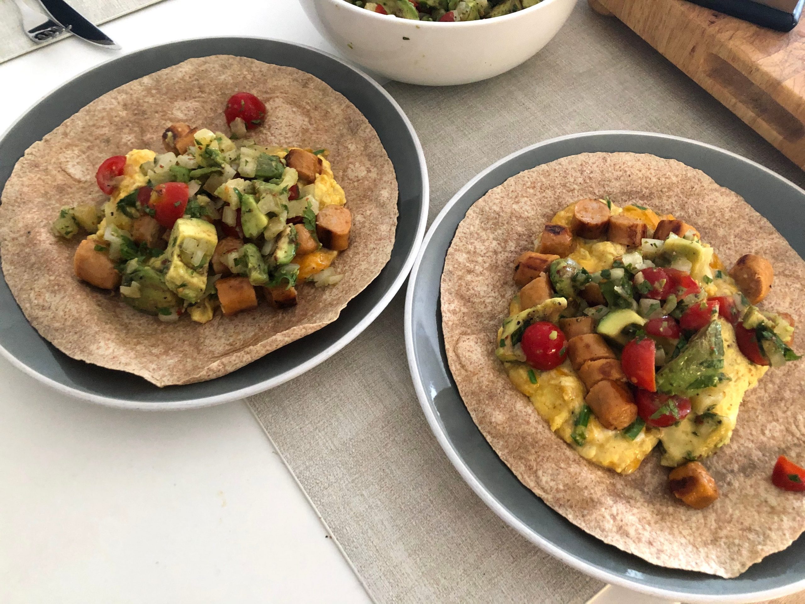 Two tortilla on plates with a lot of fillings in them, not yet folded